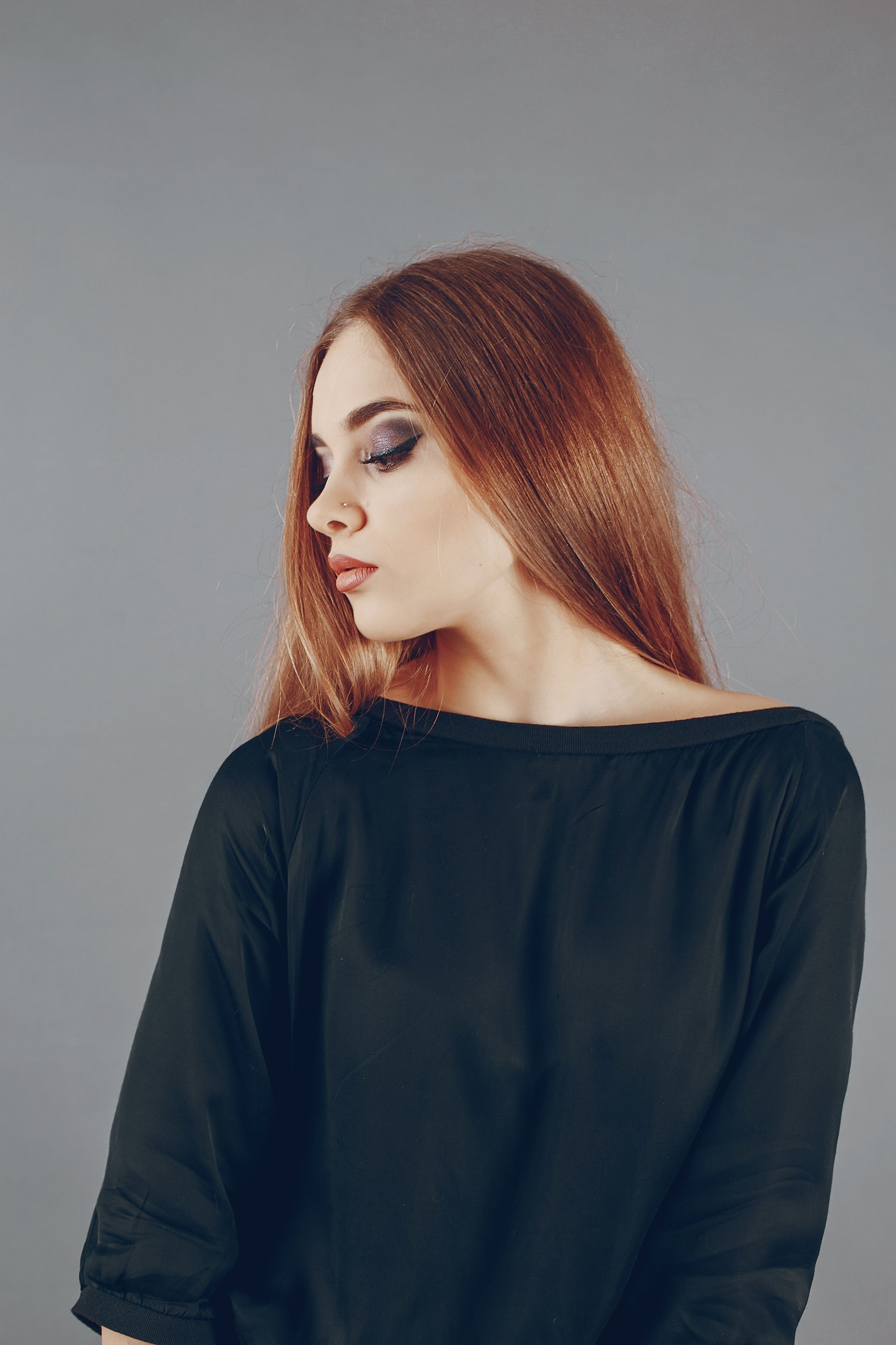 A woman with long red hair is wearing a black dress.