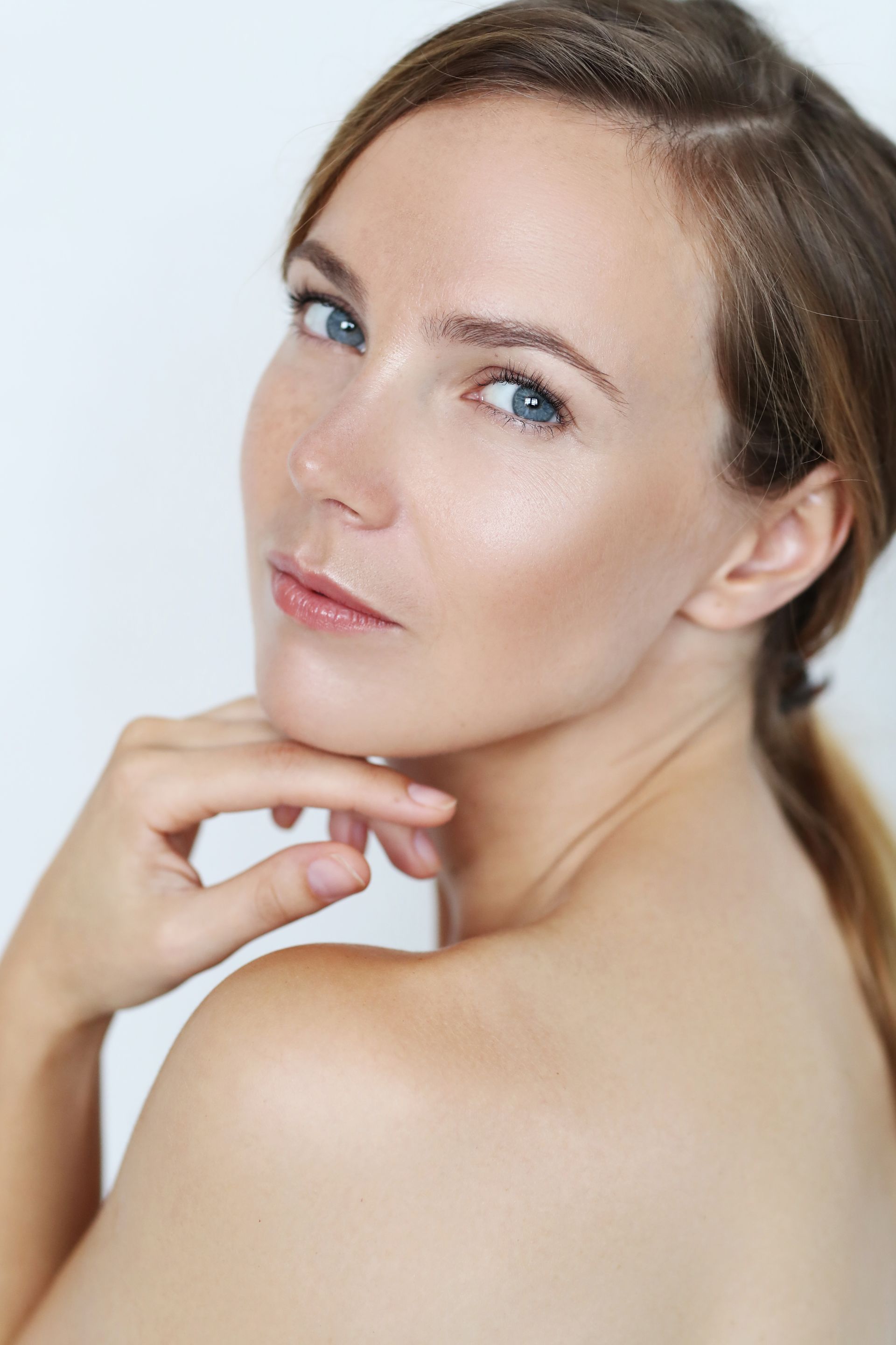 A close up of a woman 's face with her hand on her chin.