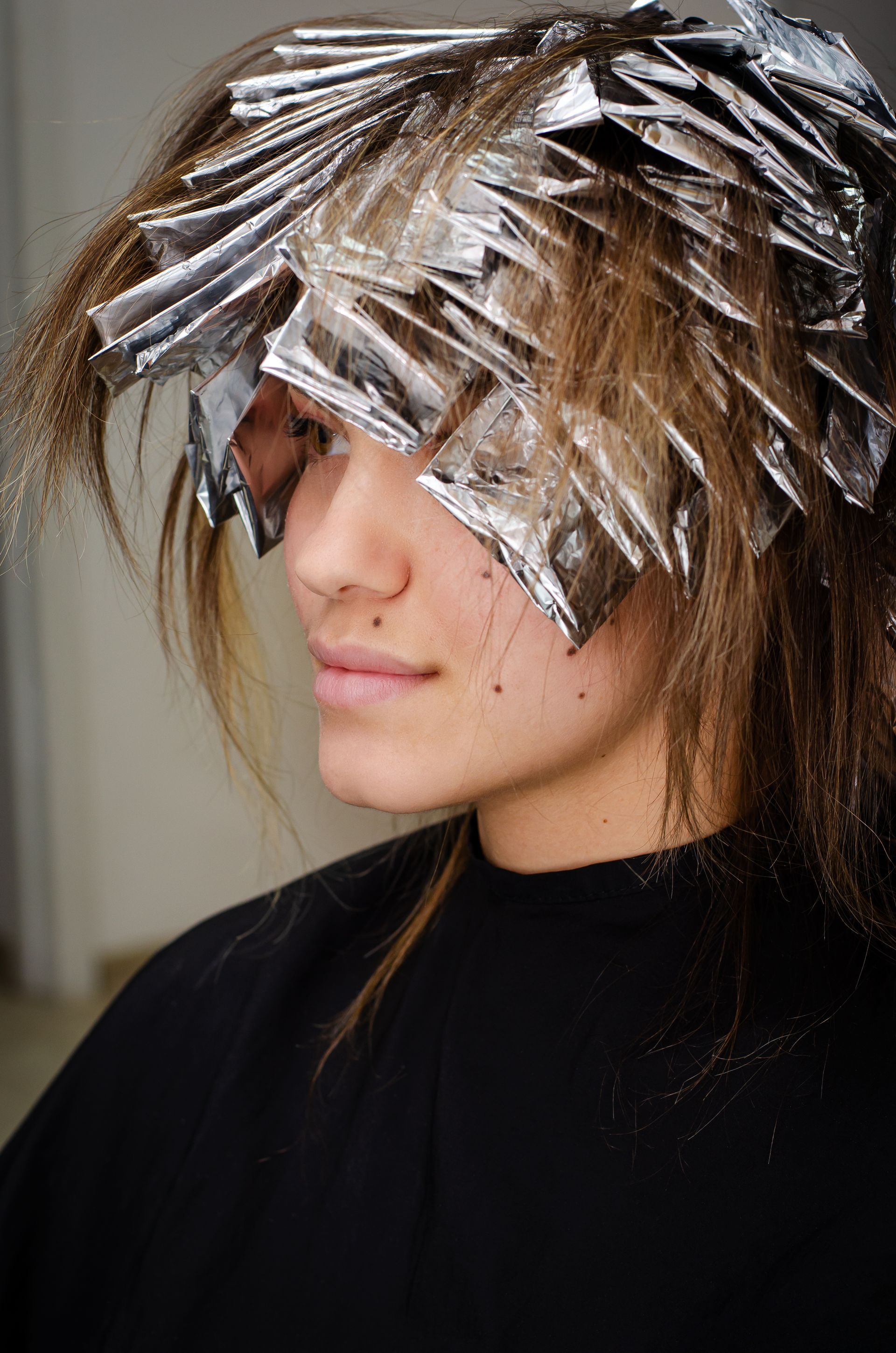 A woman is getting her hair dyed with aluminum foil.