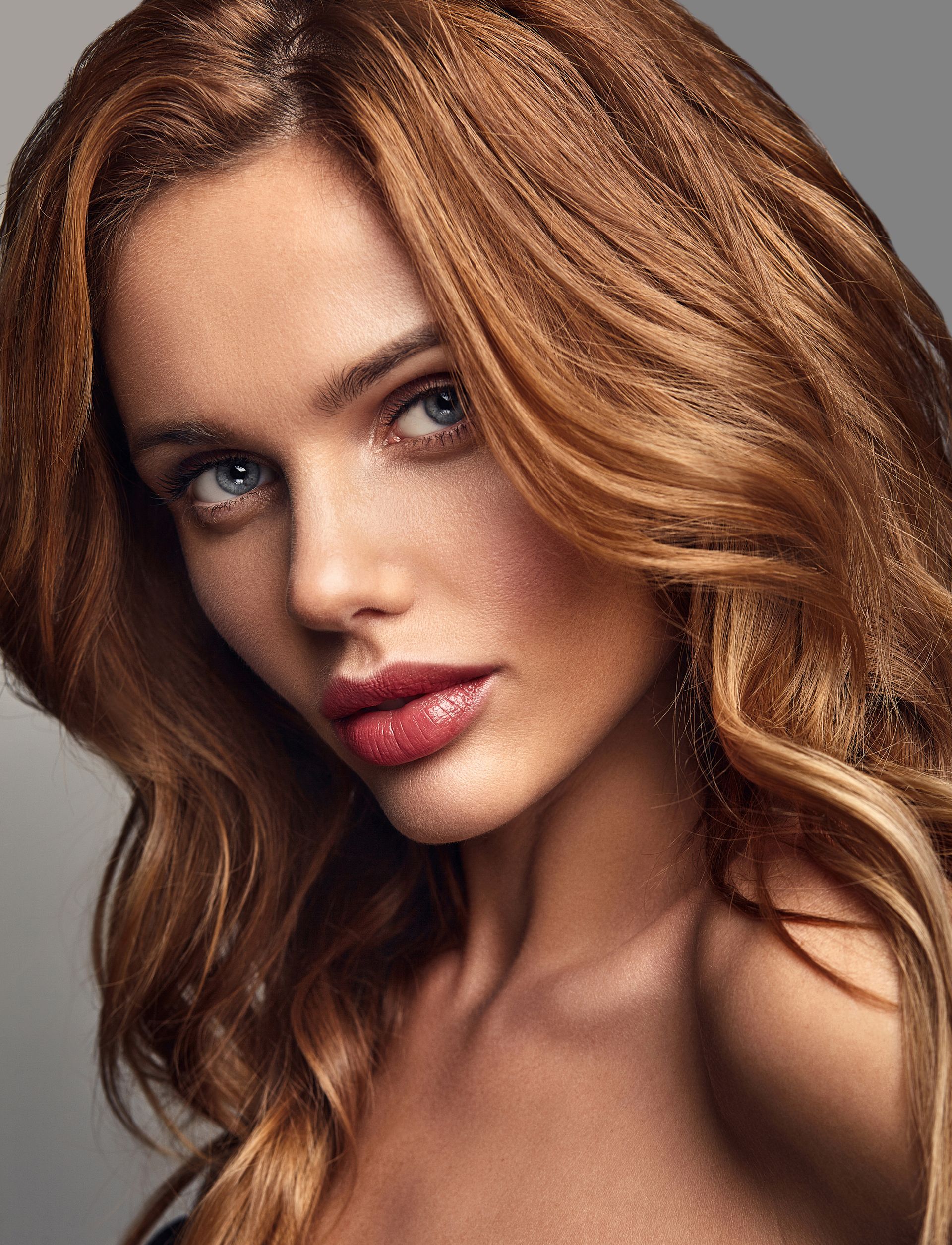 A close up of a woman 's face with long hair and red lips.