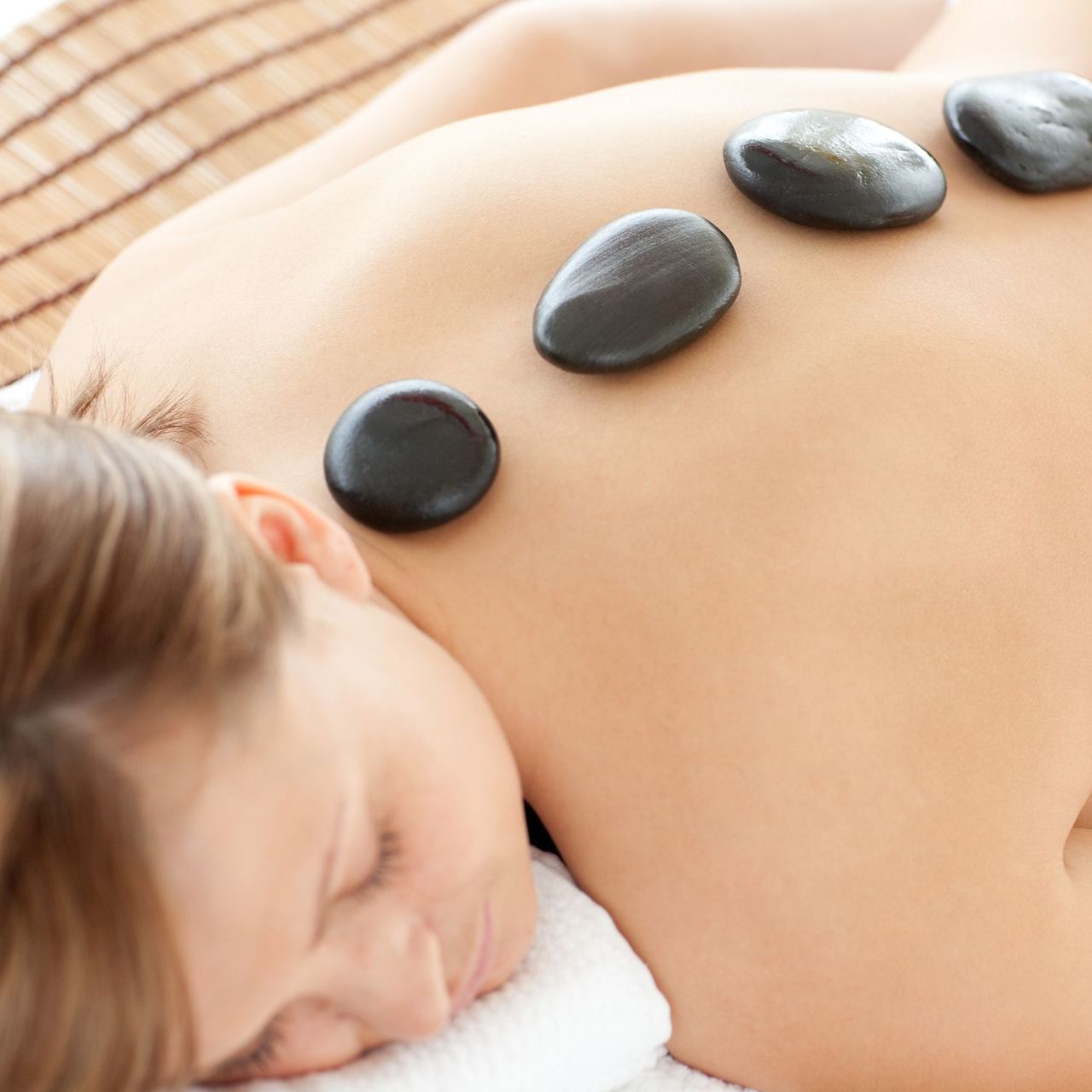 A woman is getting a massage with hot rocks on her back.