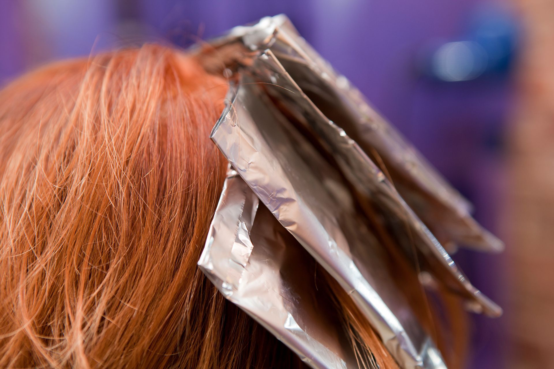 A woman is getting her hair dyed with aluminum foil.