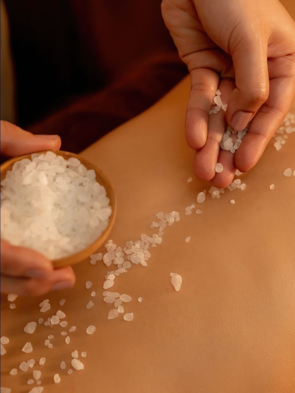 a woman getting salt scrub on her back.