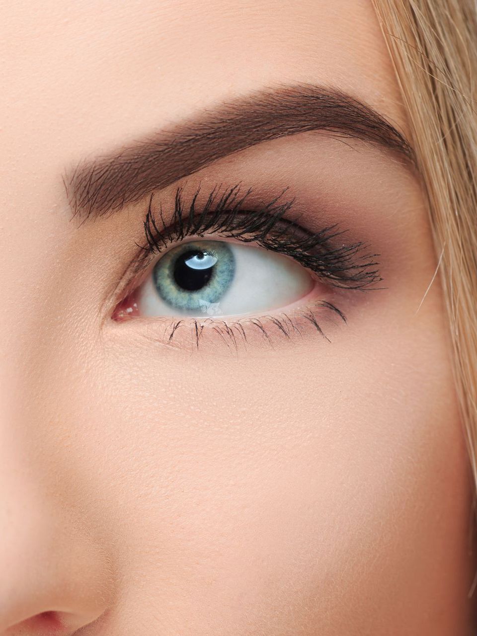 A close up of a woman 's blue eye with long eyelashes.