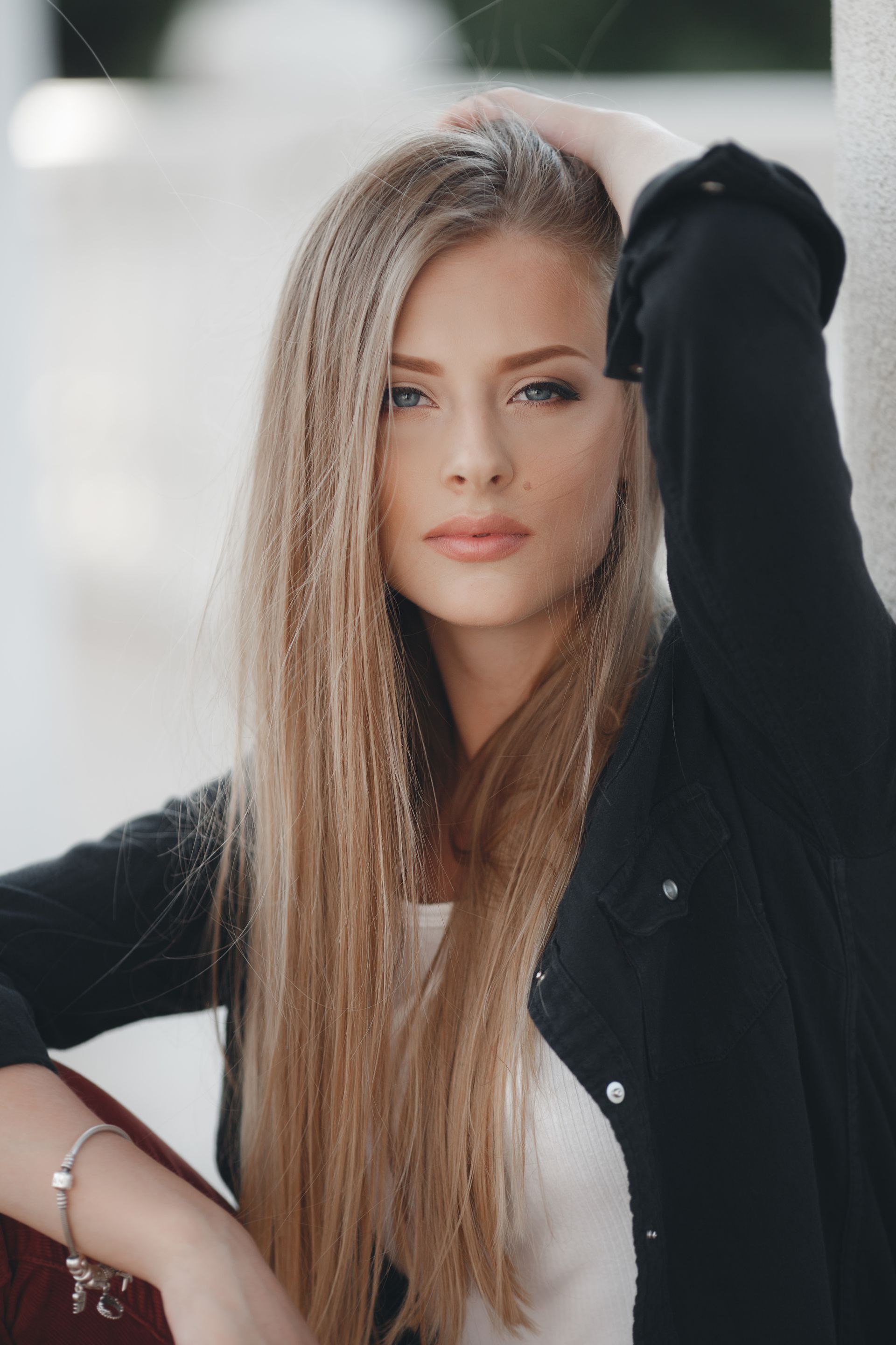 A woman with long blonde hair is wearing a black jacket and a white shirt.