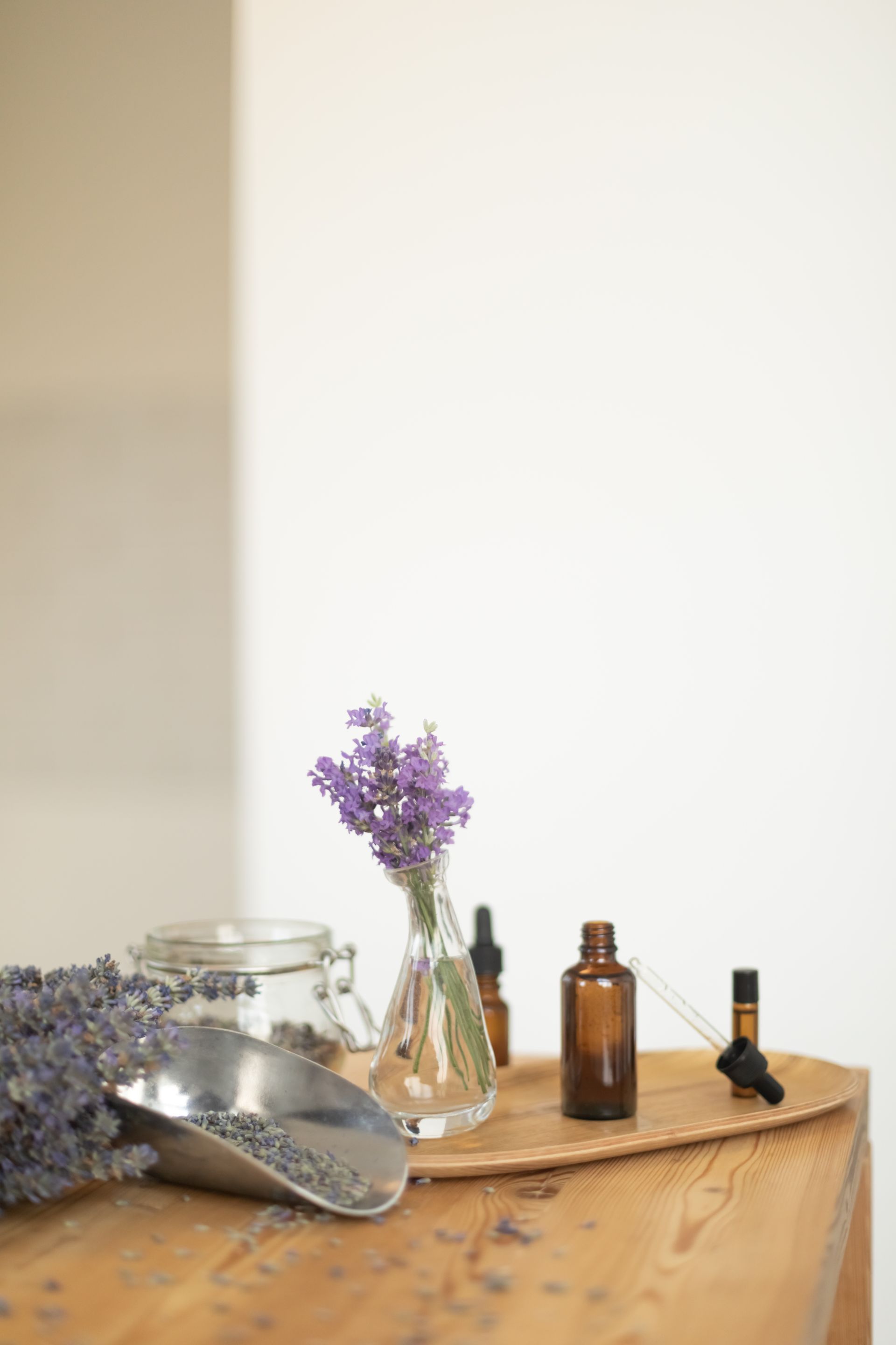 A wooden table topped with bottles of essential oils and flowers.