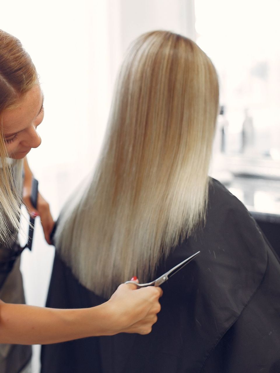 A woman is getting her hair cut by a hairdresser in a salon.