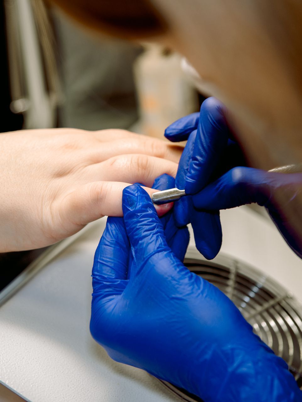 A woman is getting her nails done by a nail artist in a salon.