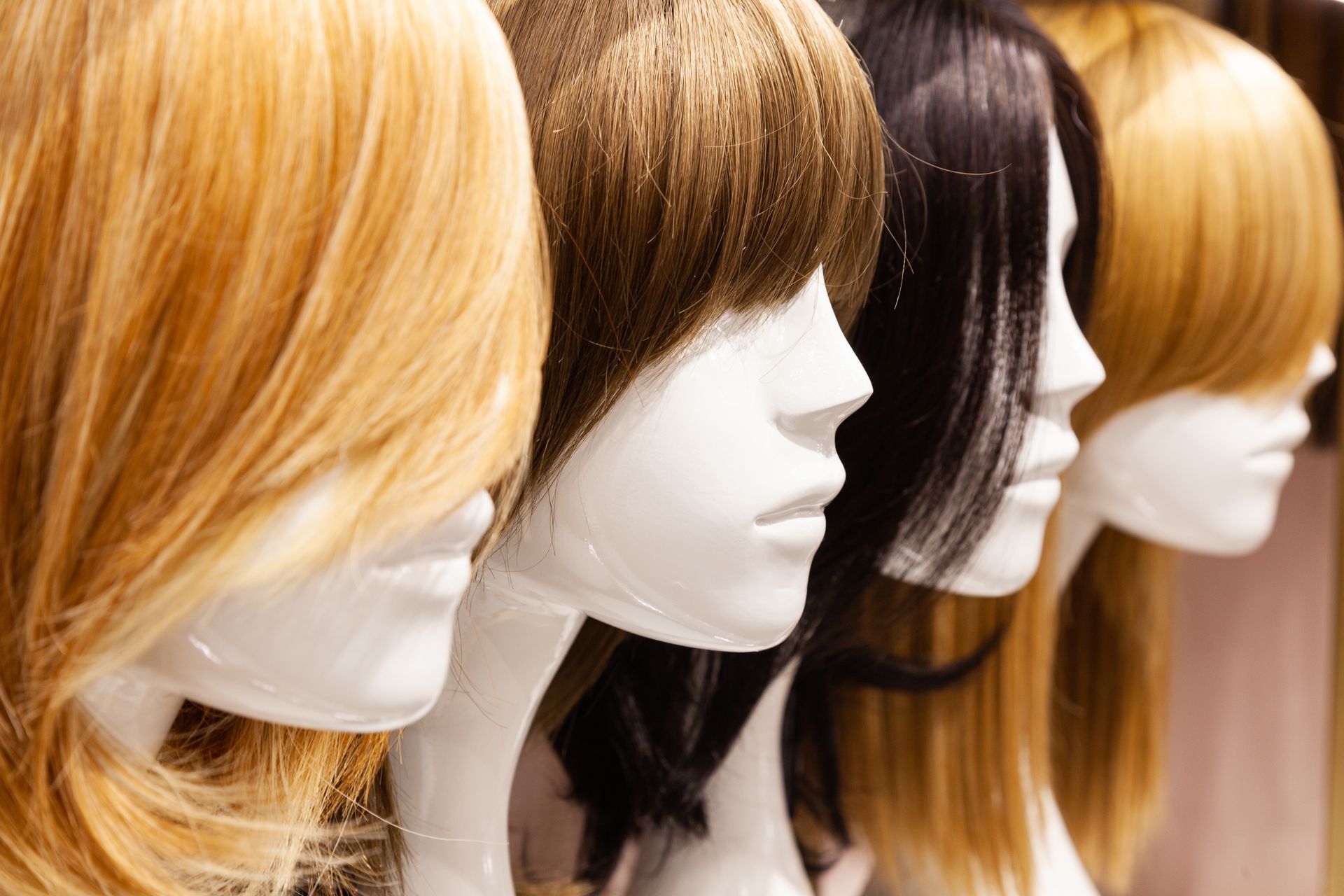 A row of mannequins wearing different colored wigs.