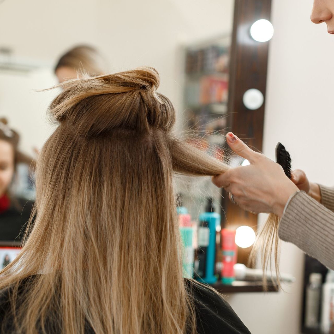 A woman is getting her hair done by a hairdresser in a salon.