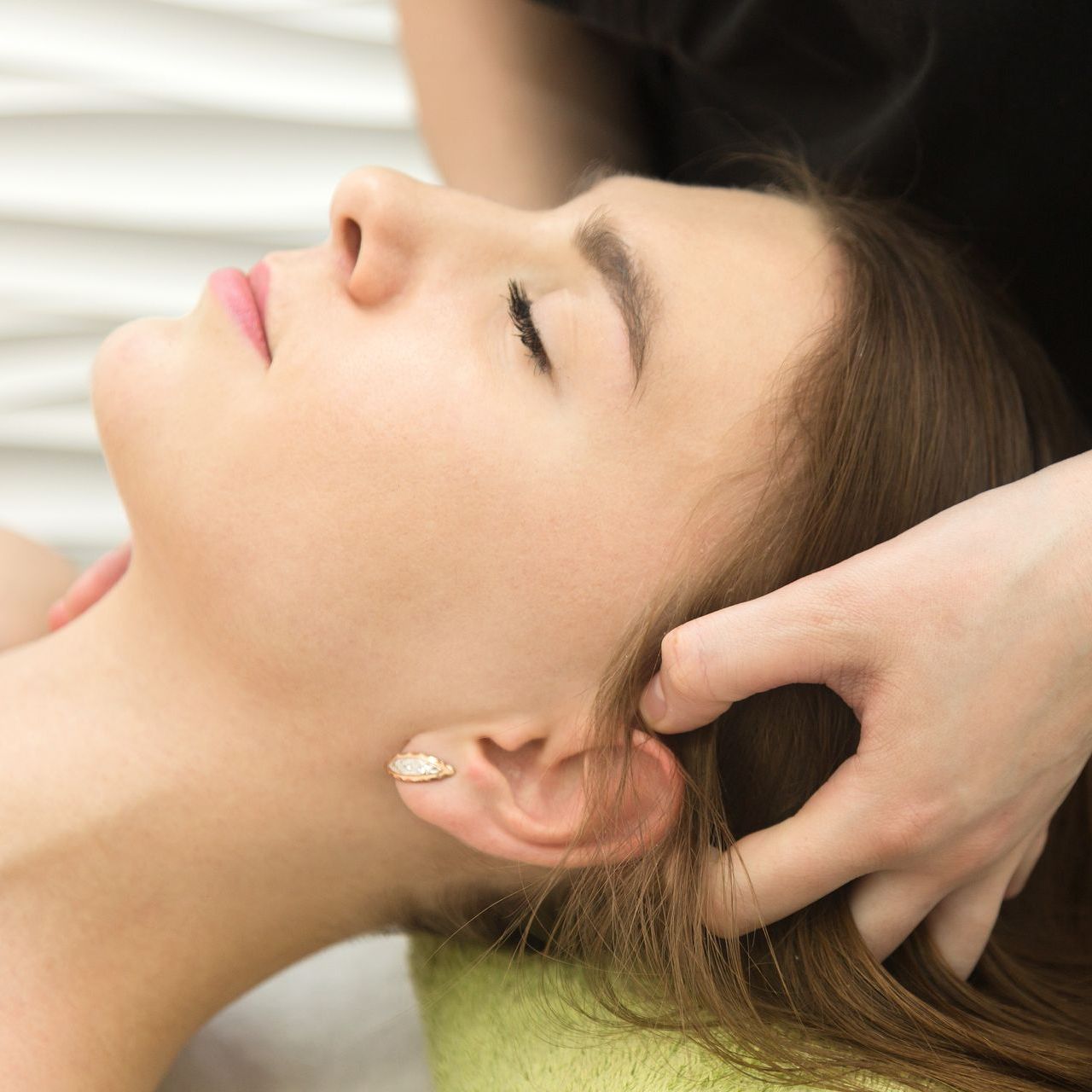 A woman is getting a head massage with her eyes closed