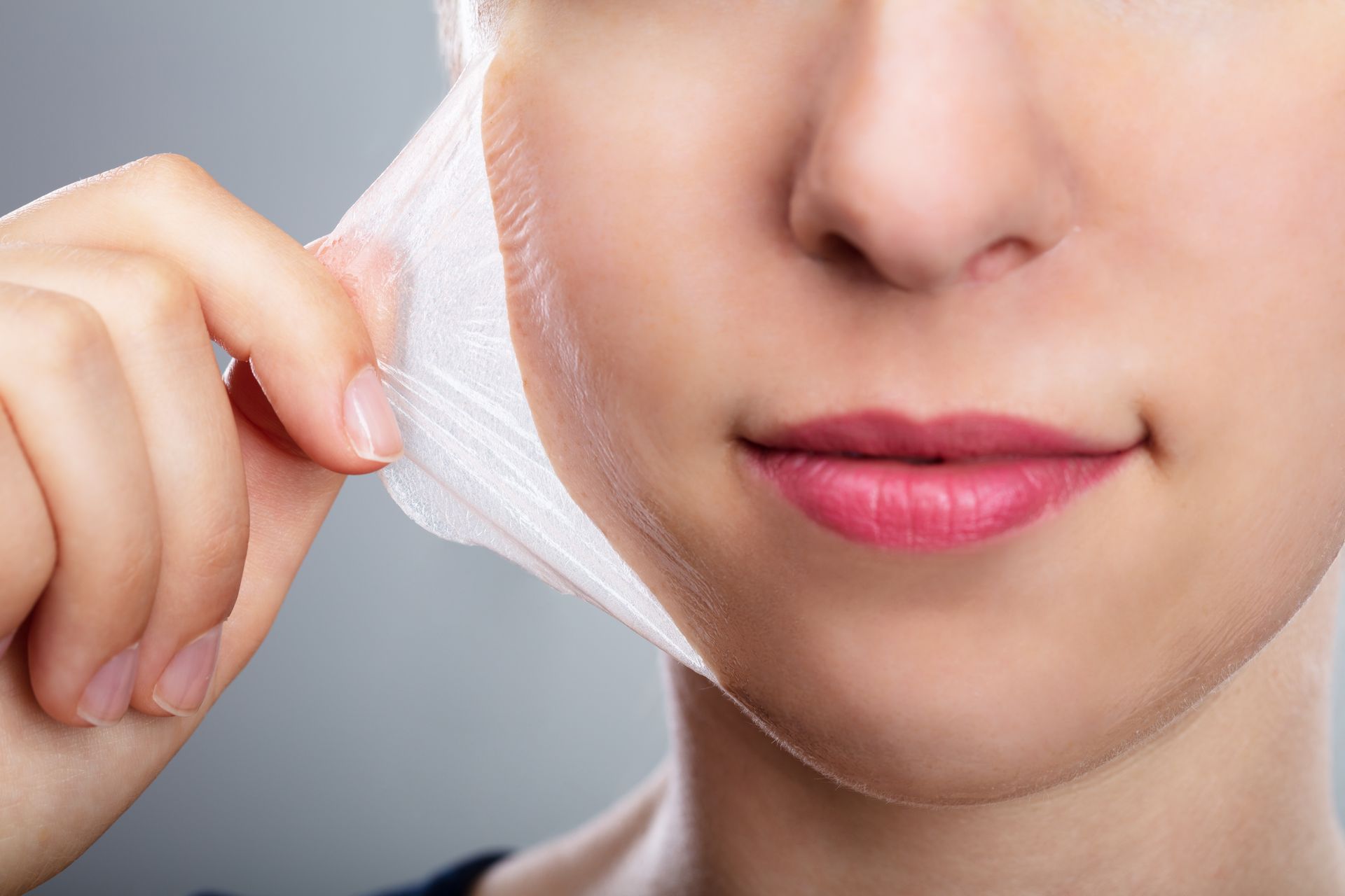 A woman is peeling off her face with a piece of paper.