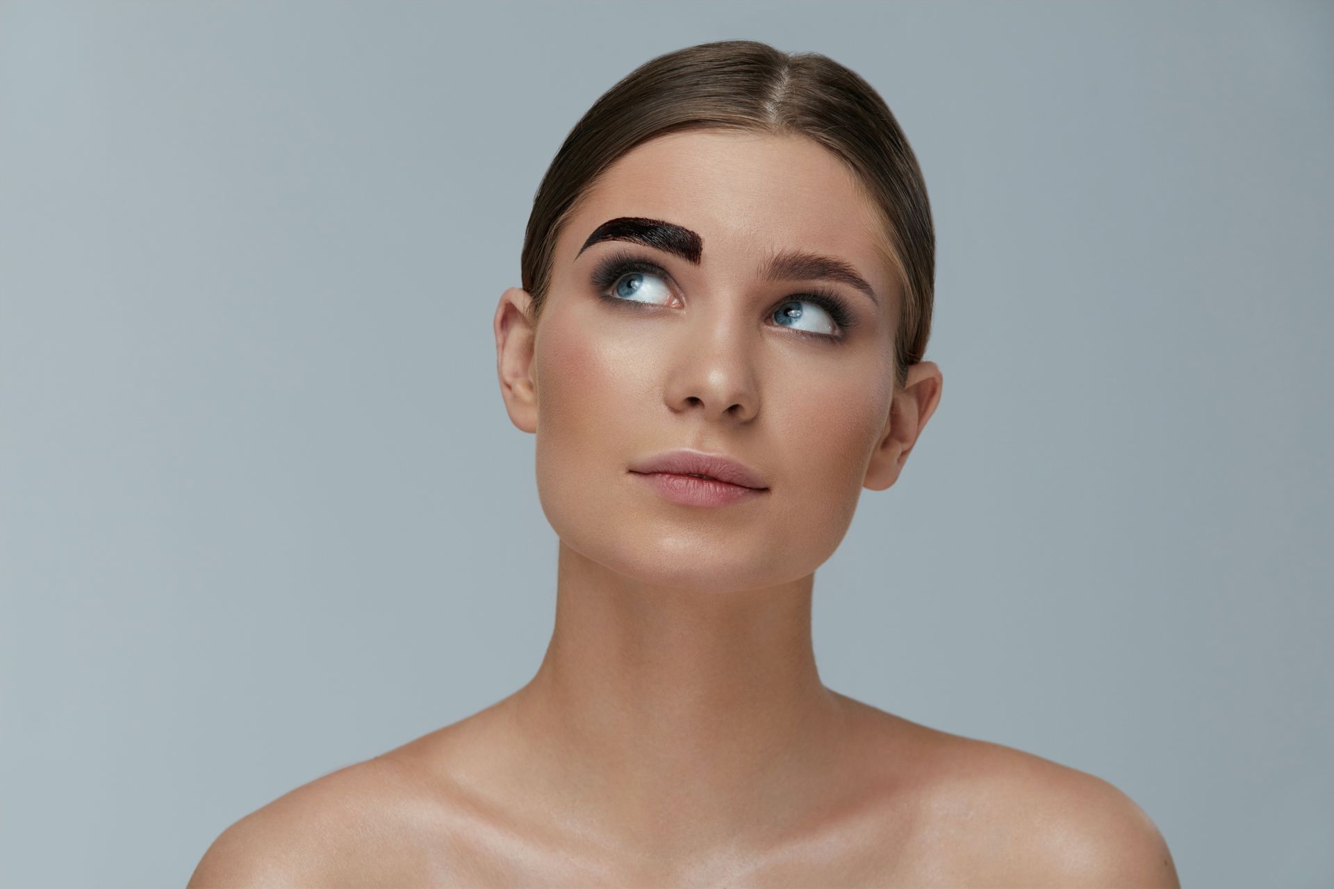 A woman with a shaved eyebrow is looking up at the sky.