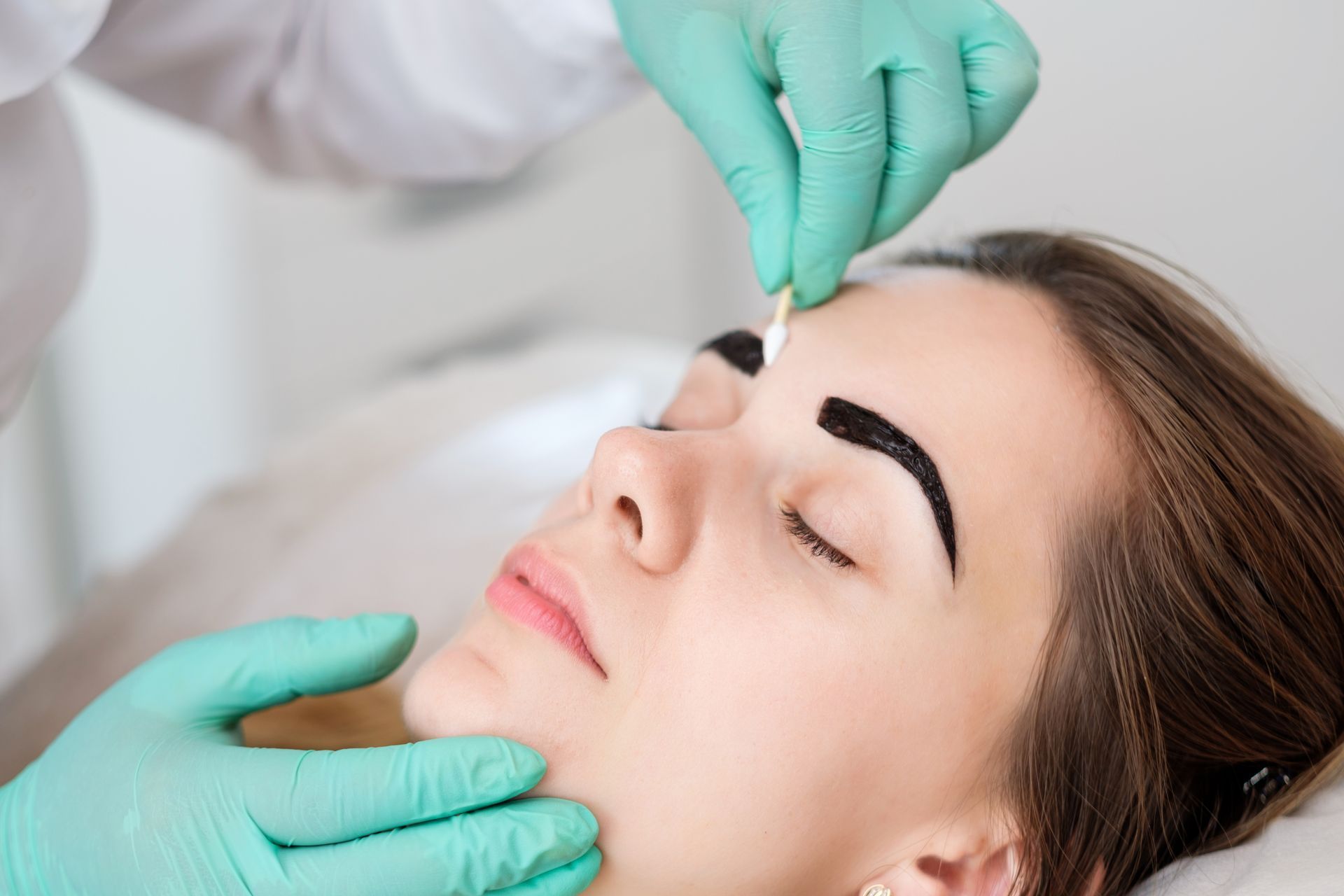 A woman is getting her eyebrows dyed in a beauty salon.