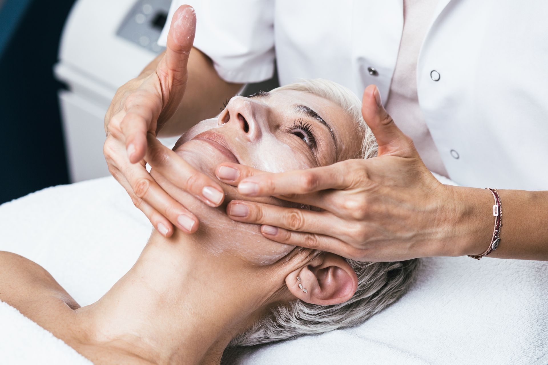 A woman is getting a facial massage at a spa.