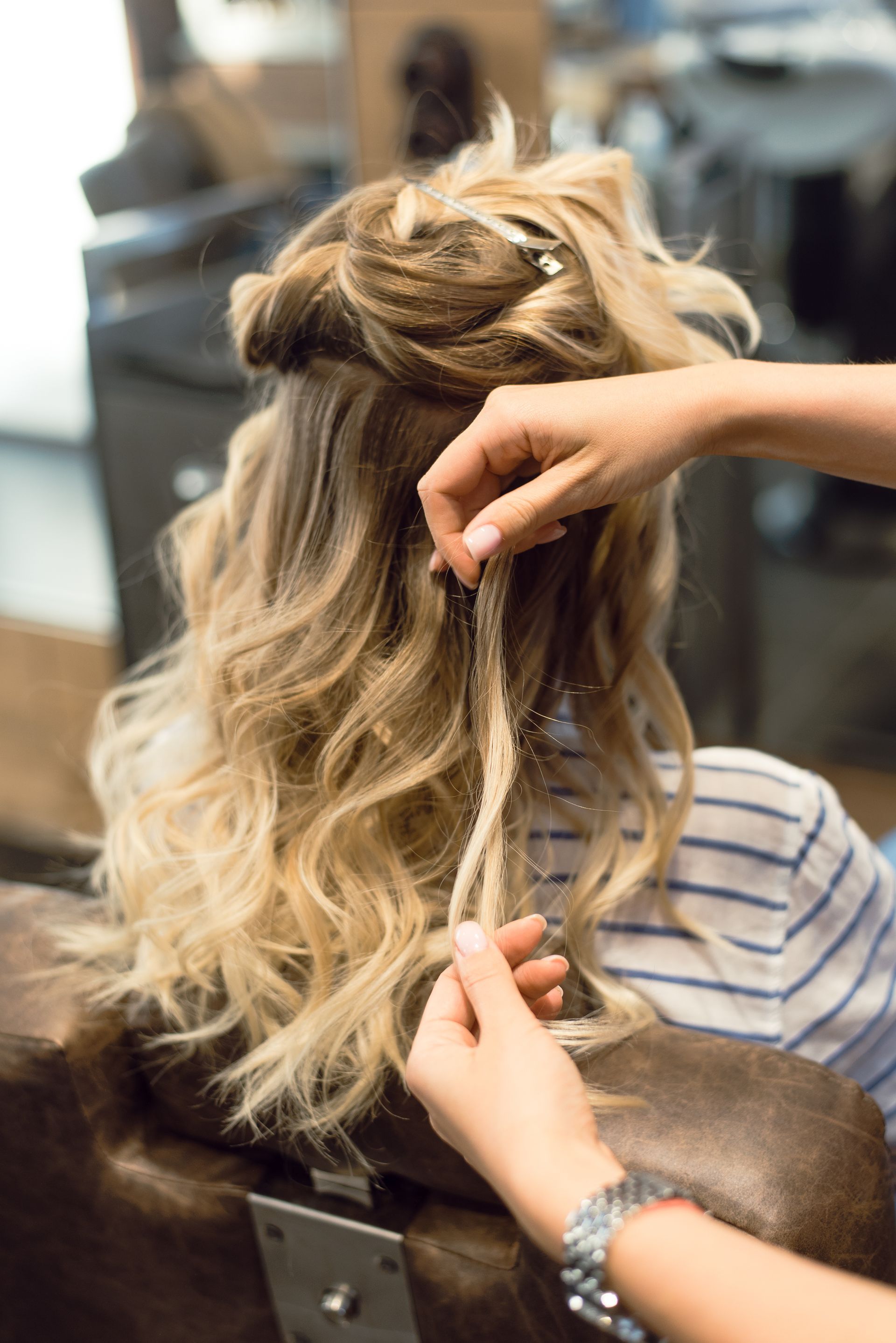 A woman is getting her hair done by a hairdresser in a salon.