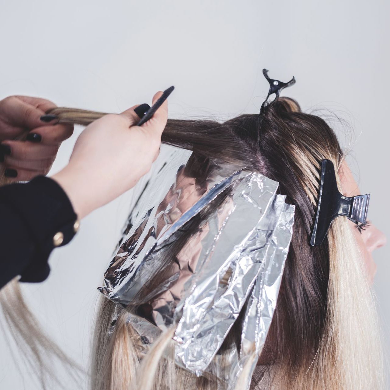 A woman is getting her hair dyed by a hairdresser.