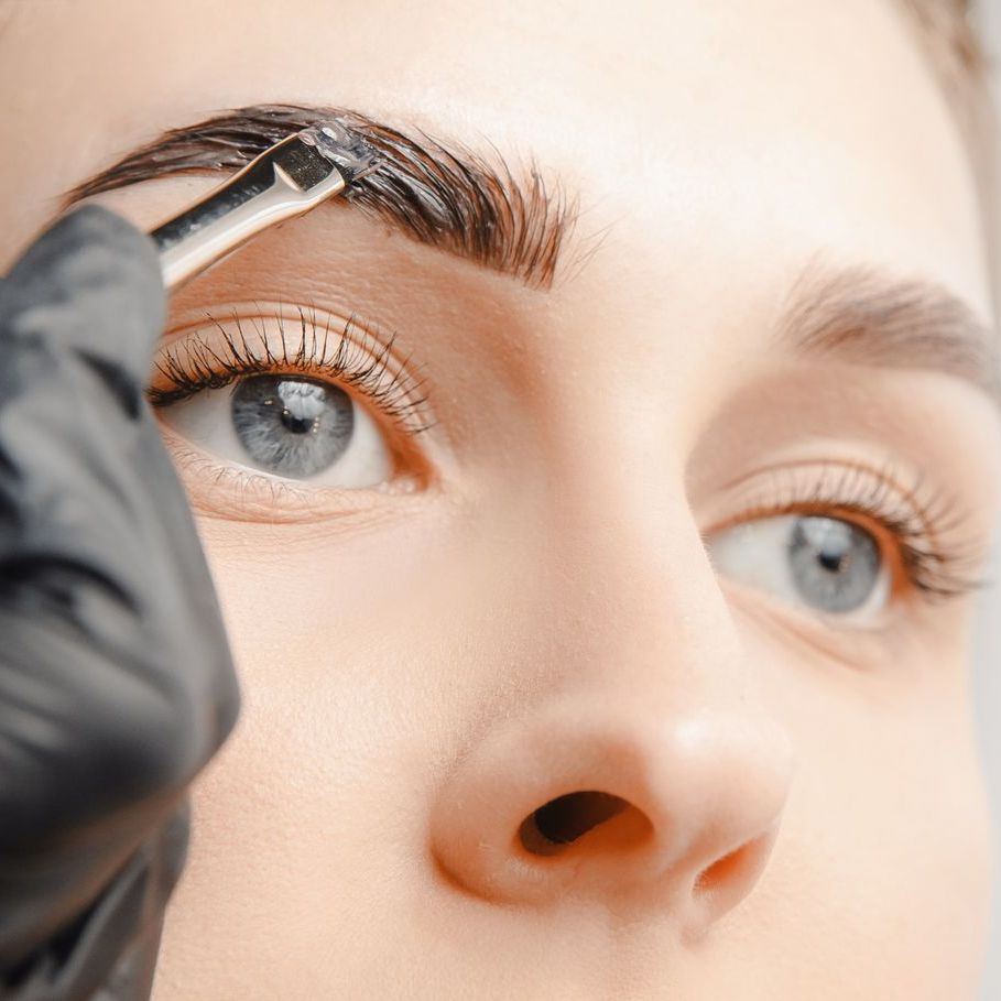 A close up of a woman getting her eyebrows painted.