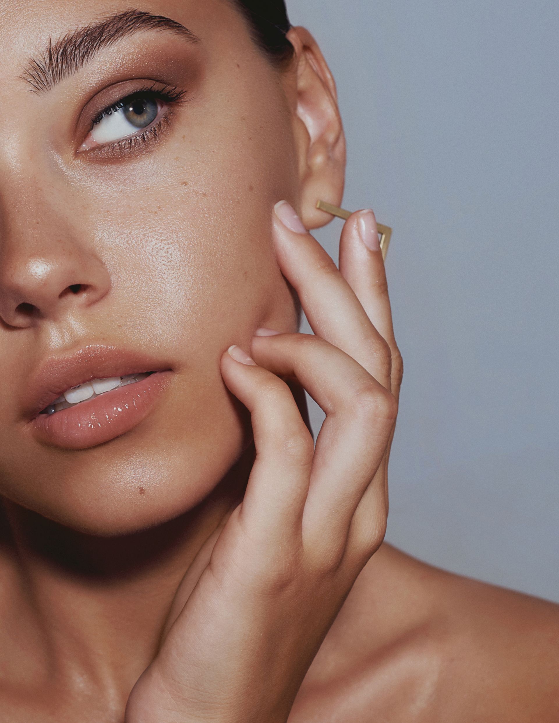 A close up of a woman 's face with her hand on her ear.