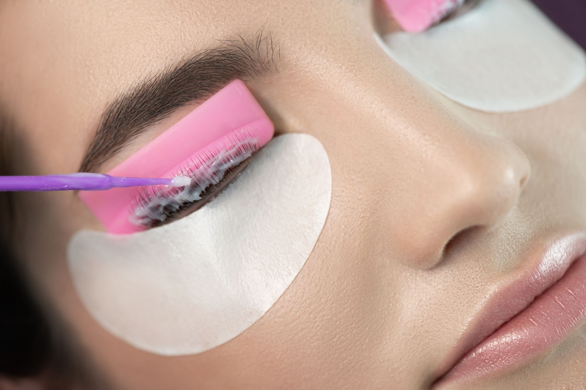 A woman is getting her eyelashes laminated in a beauty salon.