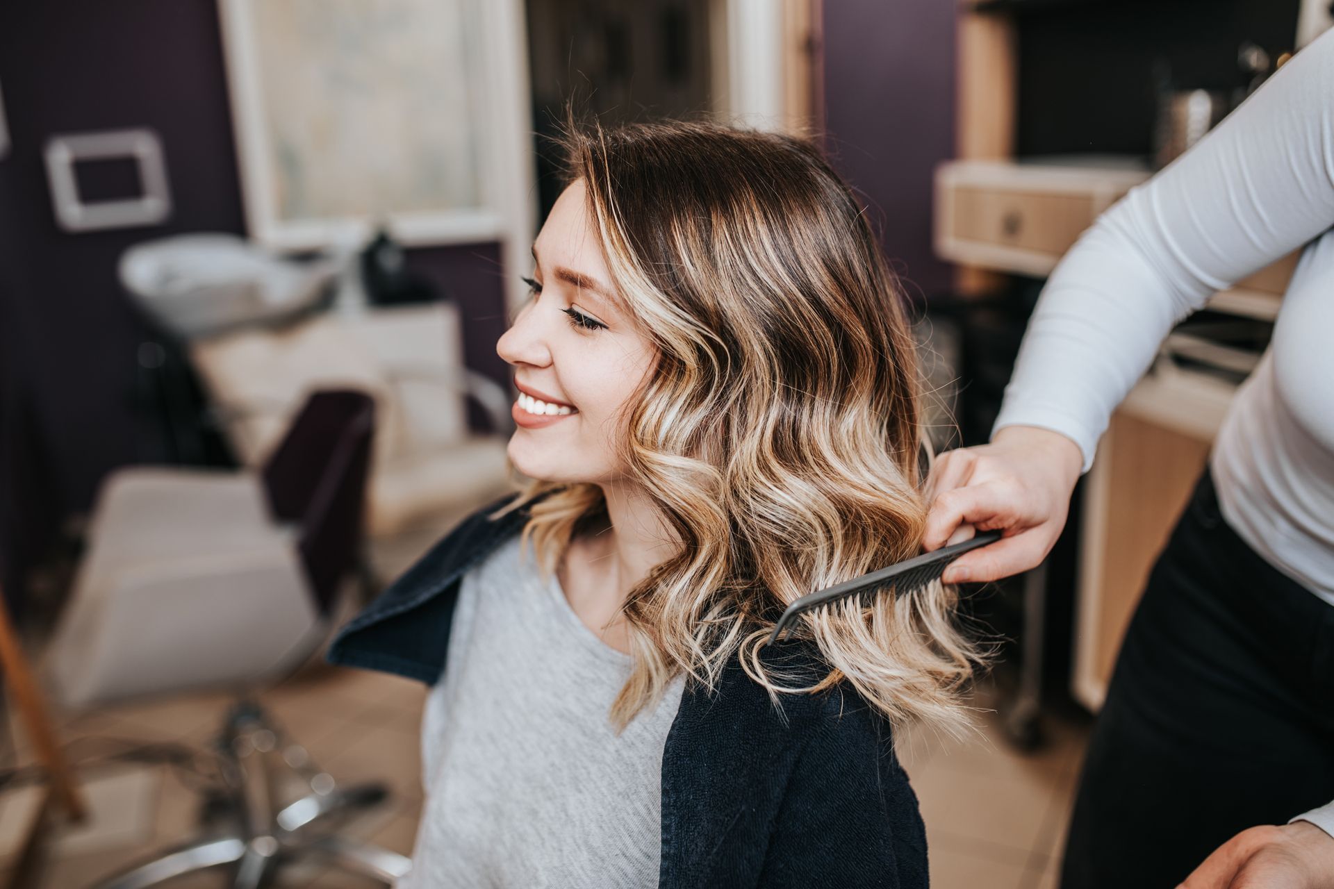 A woman is getting her hair done by a hairdresser in a salon.