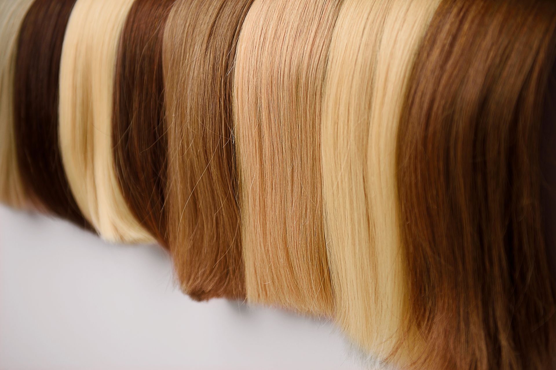 A row of different colored hair extensions hanging on a wall.