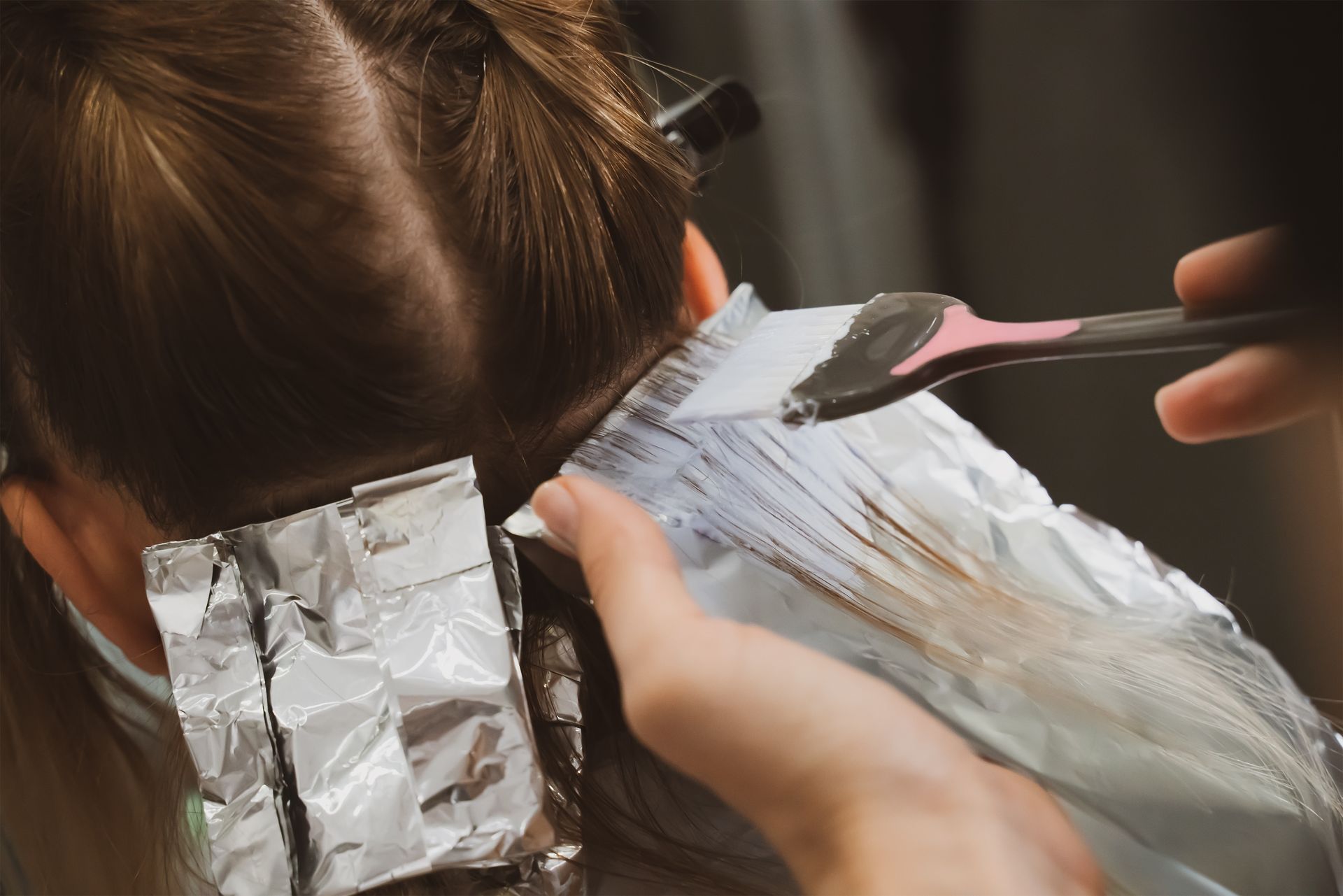 A woman is getting her hair dyed by a hairdresser.