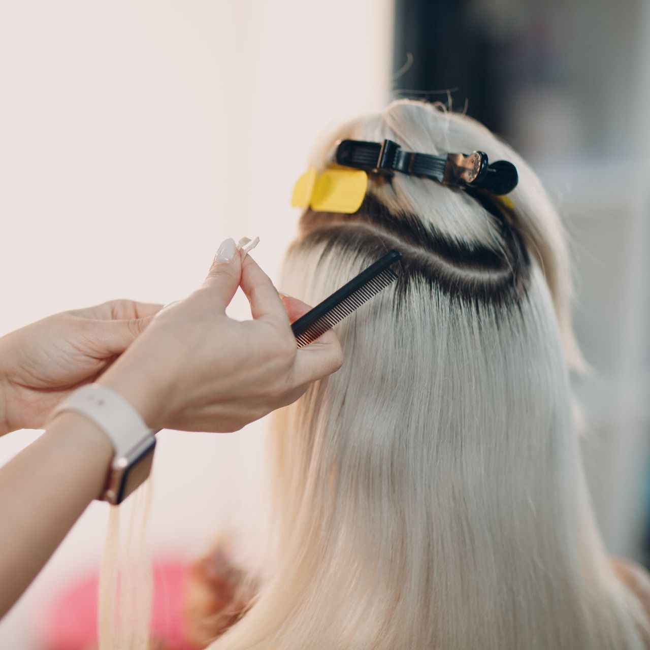 A woman is getting her hair done by a hairdresser