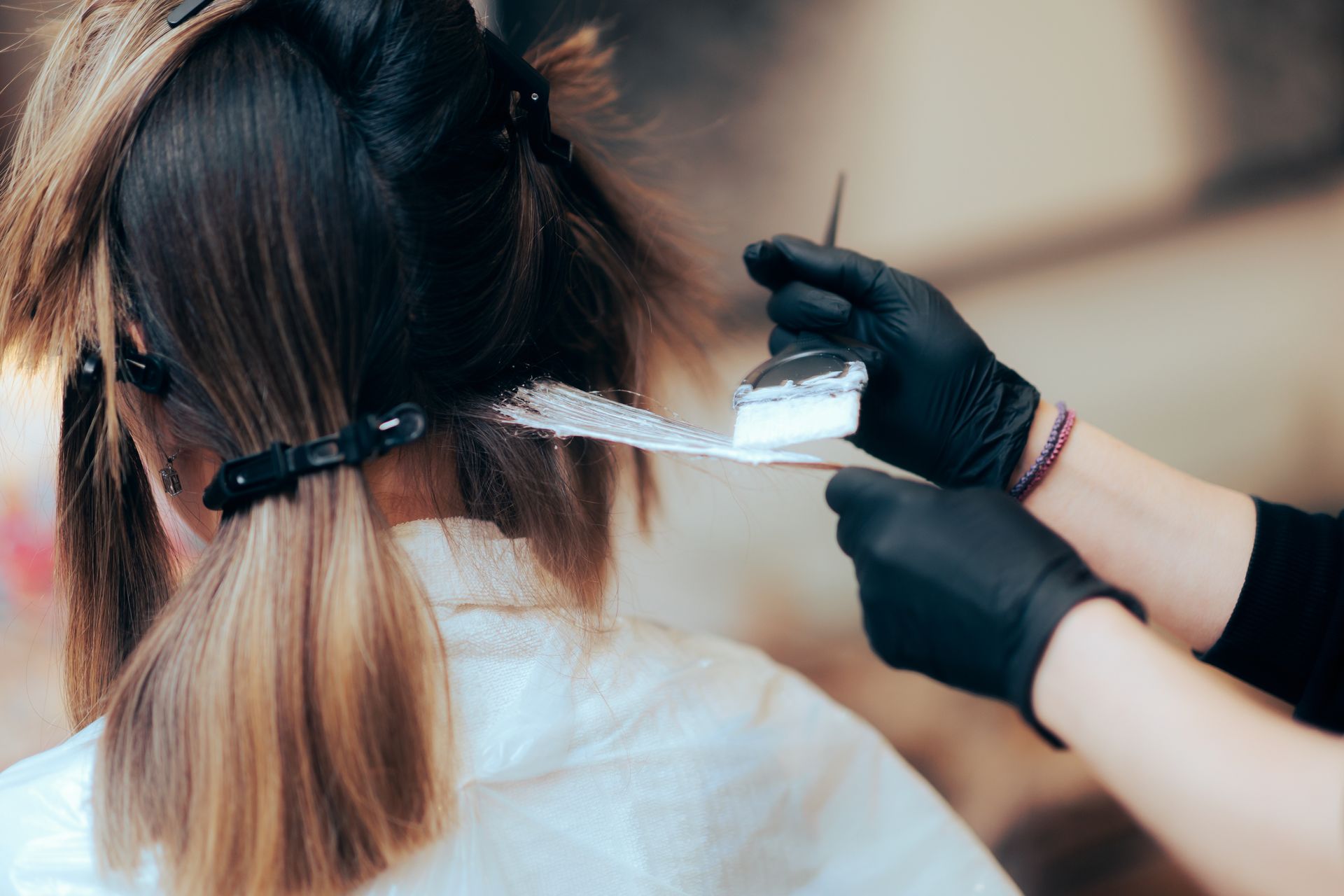 A woman is getting her hair dyed by a hairdresser in a salon.