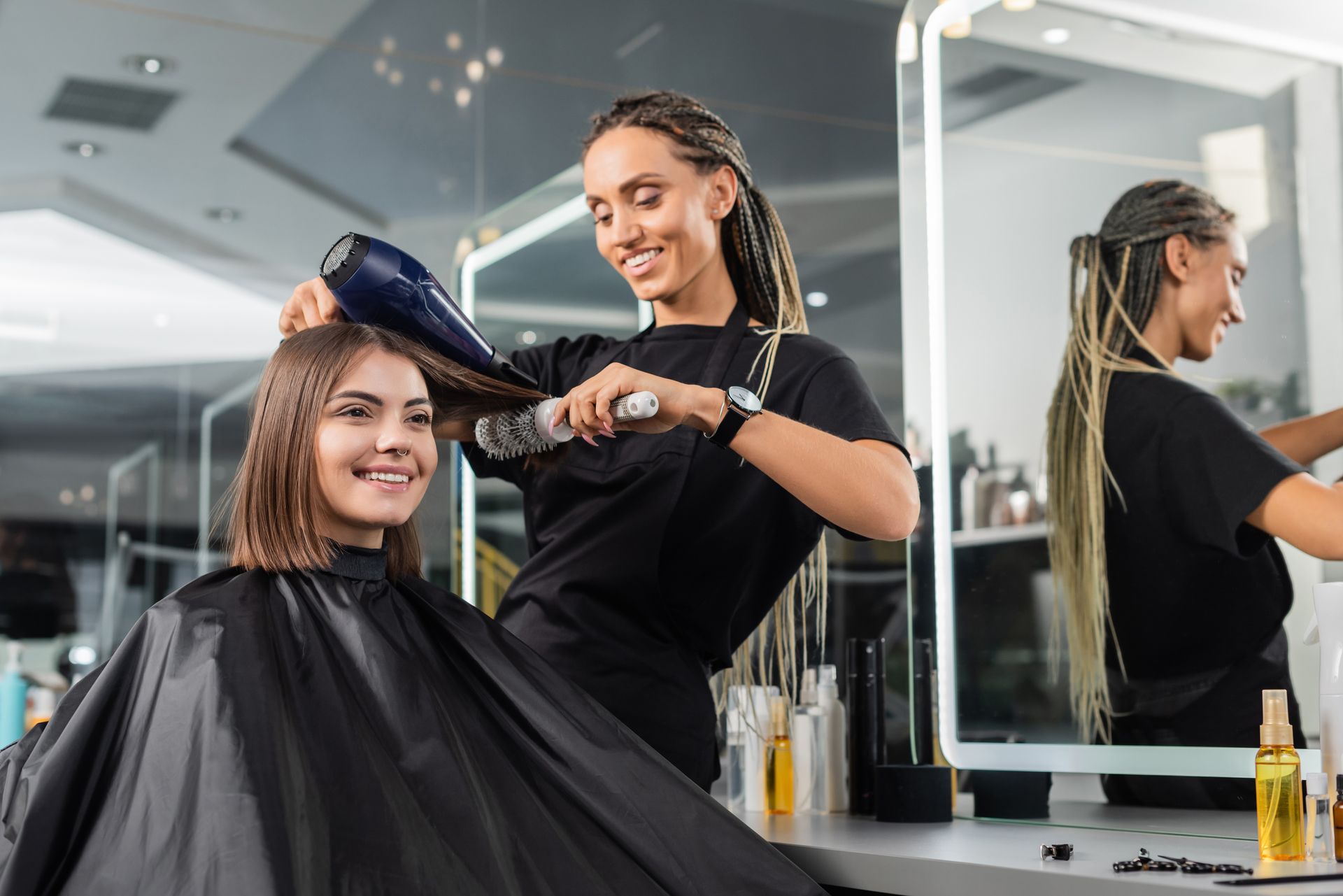 A woman is getting her hair blow dried by a hairdresser in a salon.