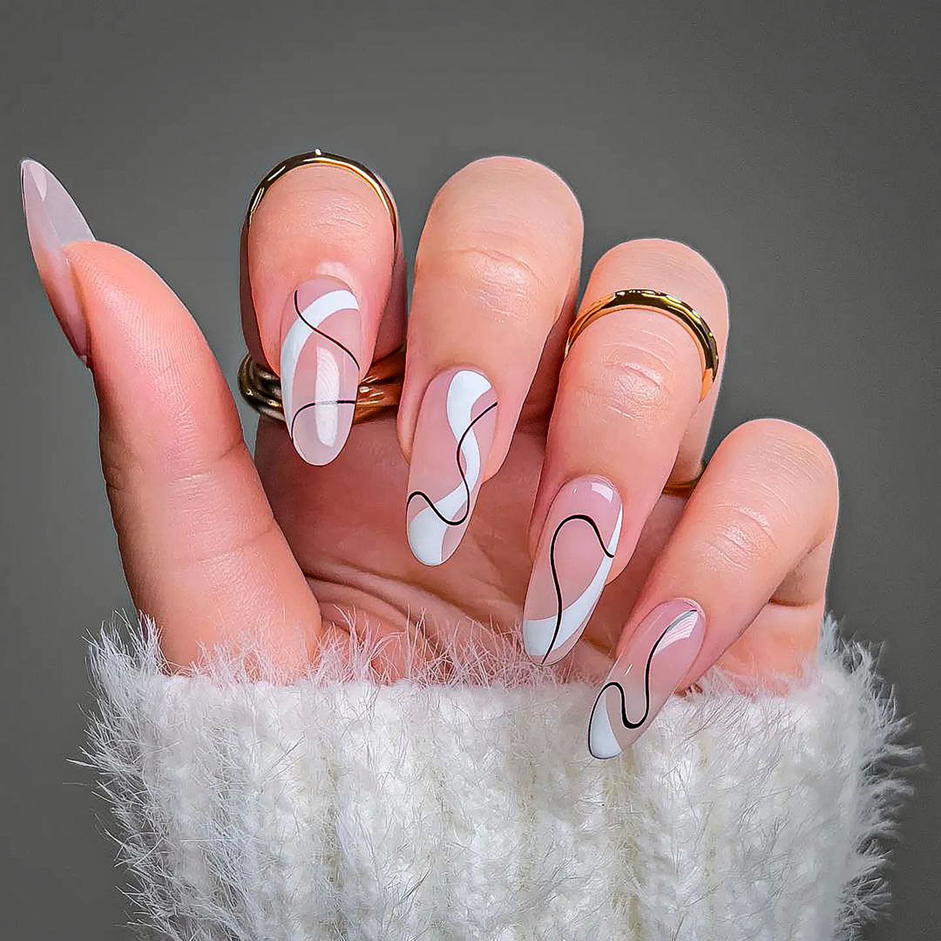 A close up of a woman 's hand with long nails and rings.