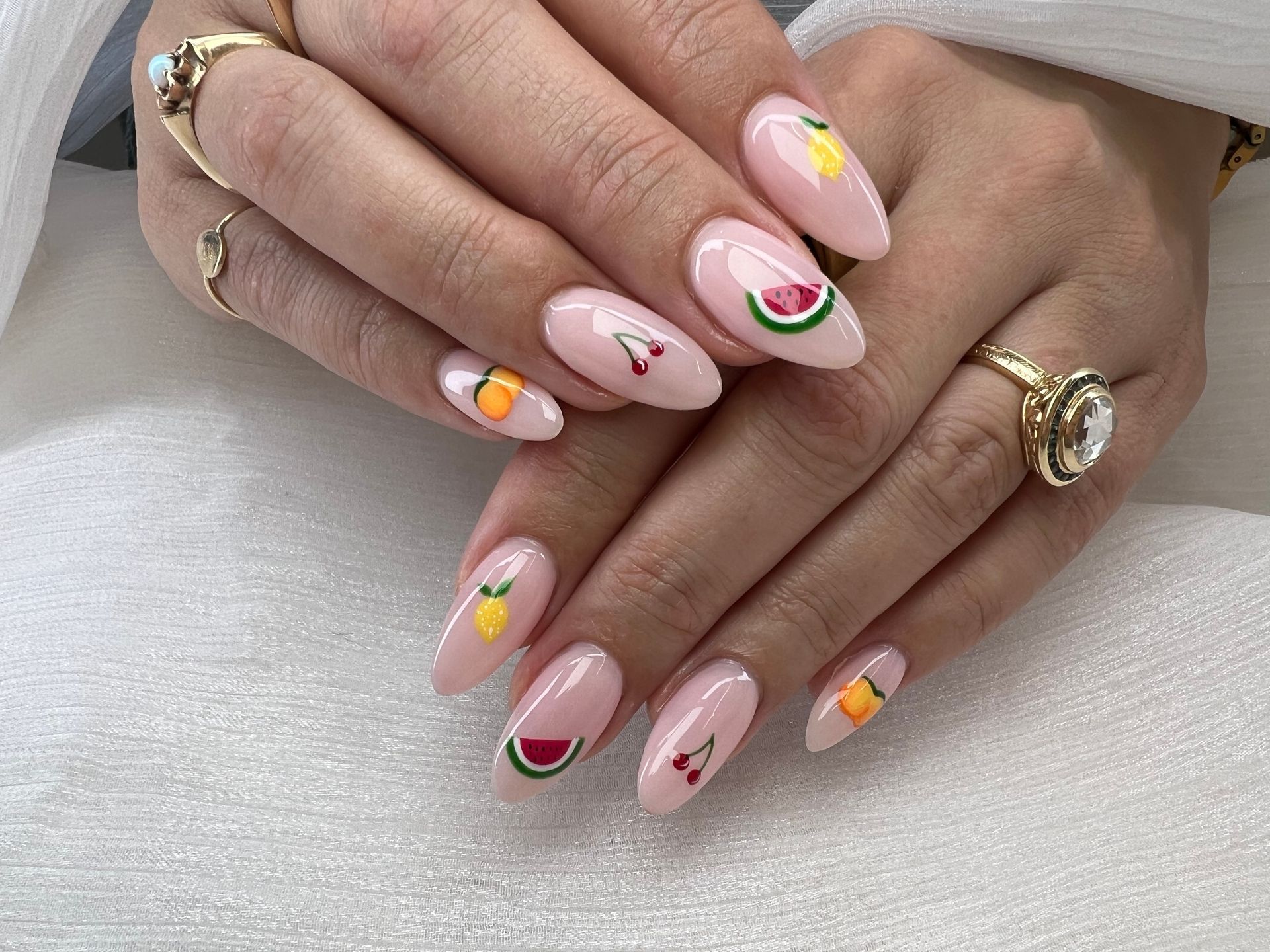 A close up of a woman 's nails with fruit designs on them.