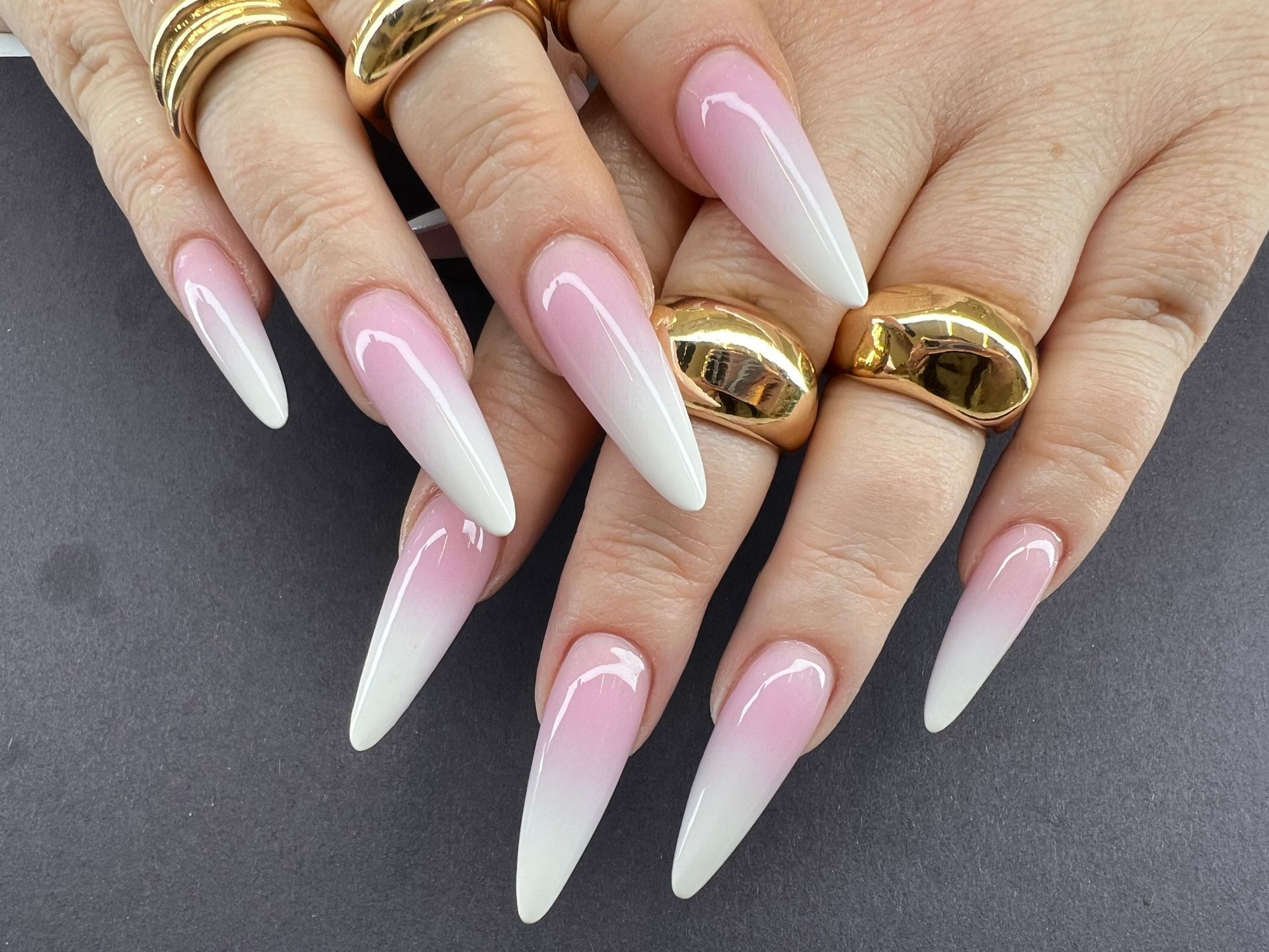 A close up of a woman 's nails with gold rings