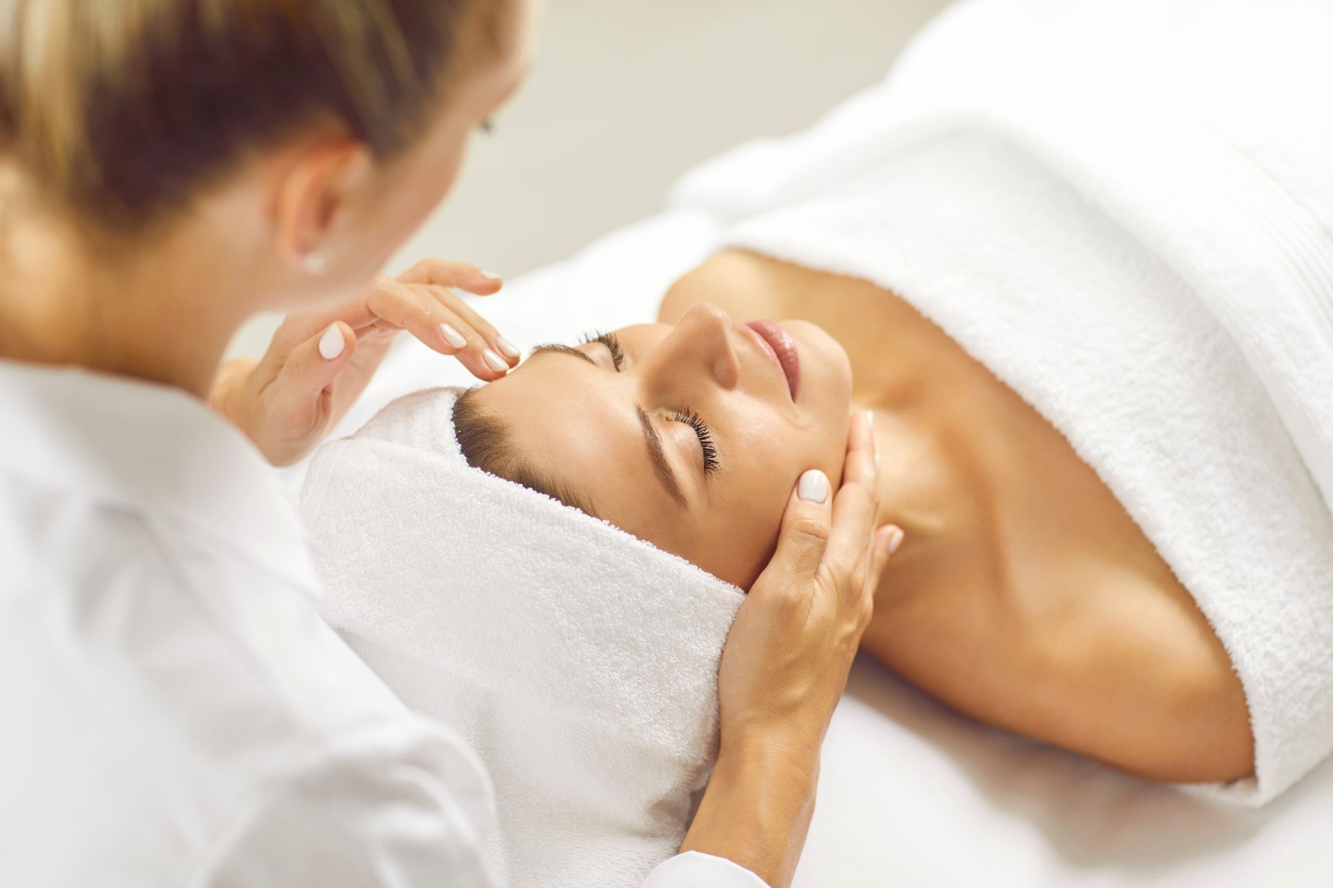 A woman is getting a facial massage at a spa.