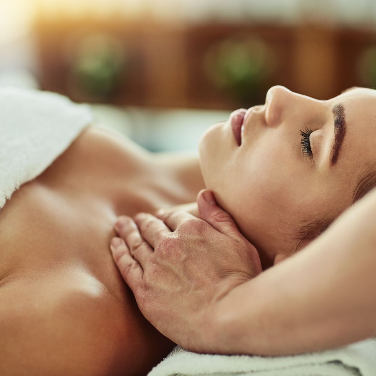 A woman is getting a massage at a spa with her eyes closed.