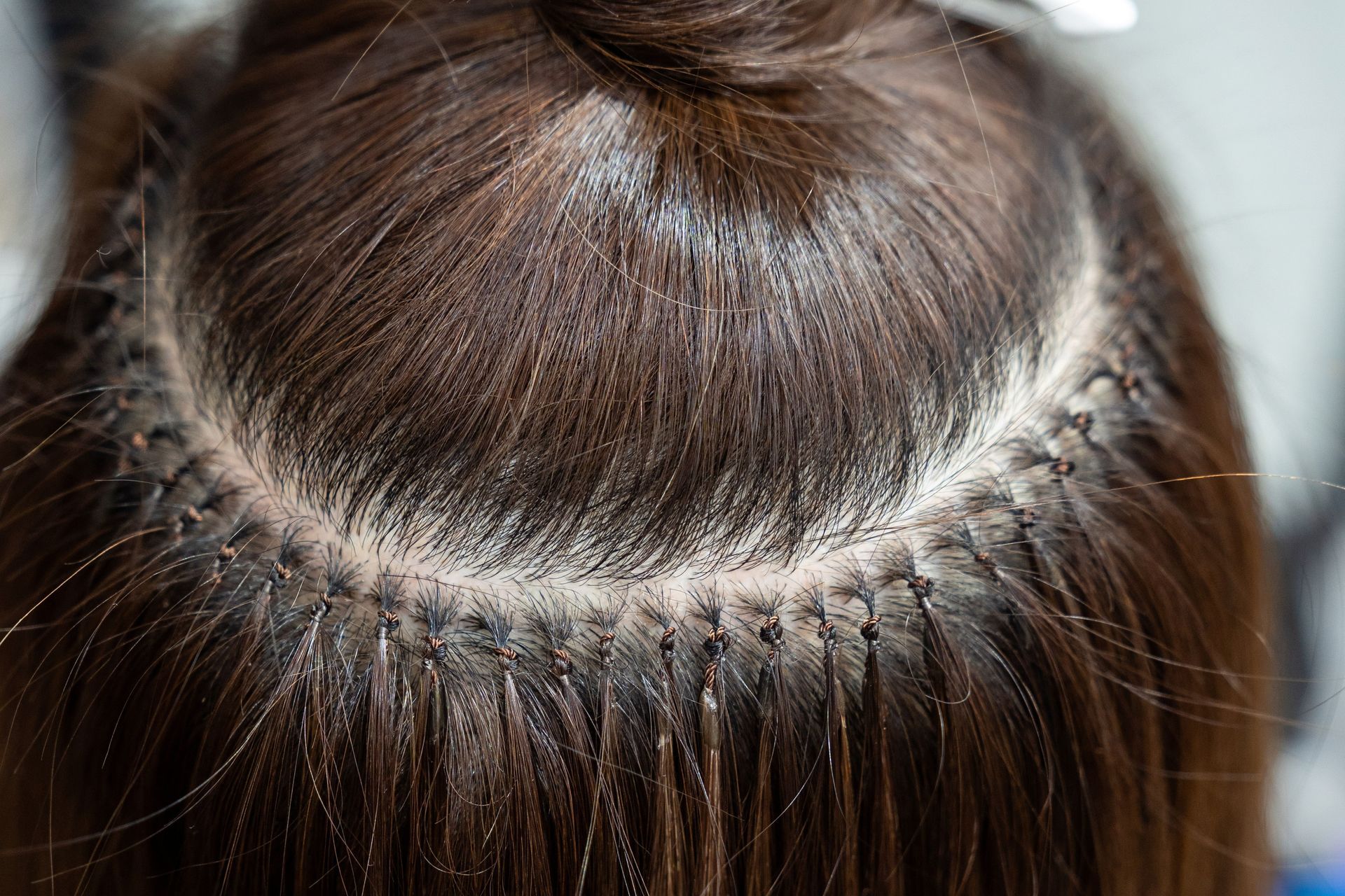 A woman is getting her hair extensions done at a salon.