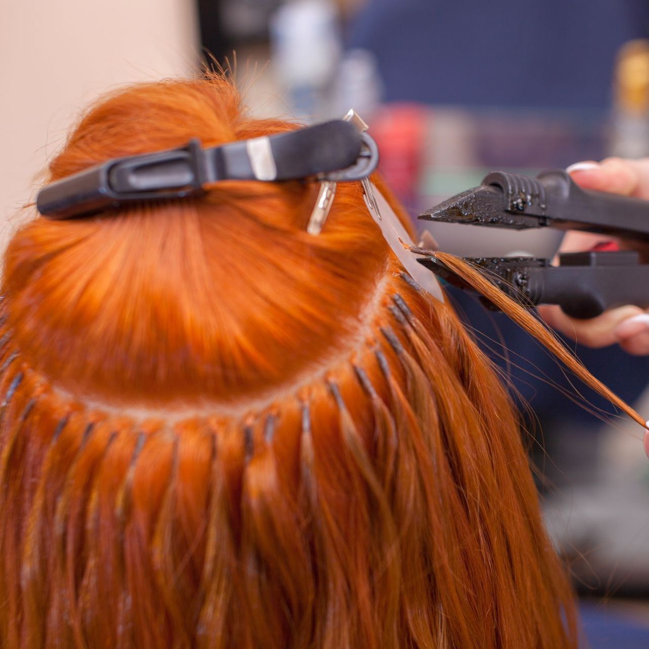 A woman with red hair is getting her hair done by a hairdresser.