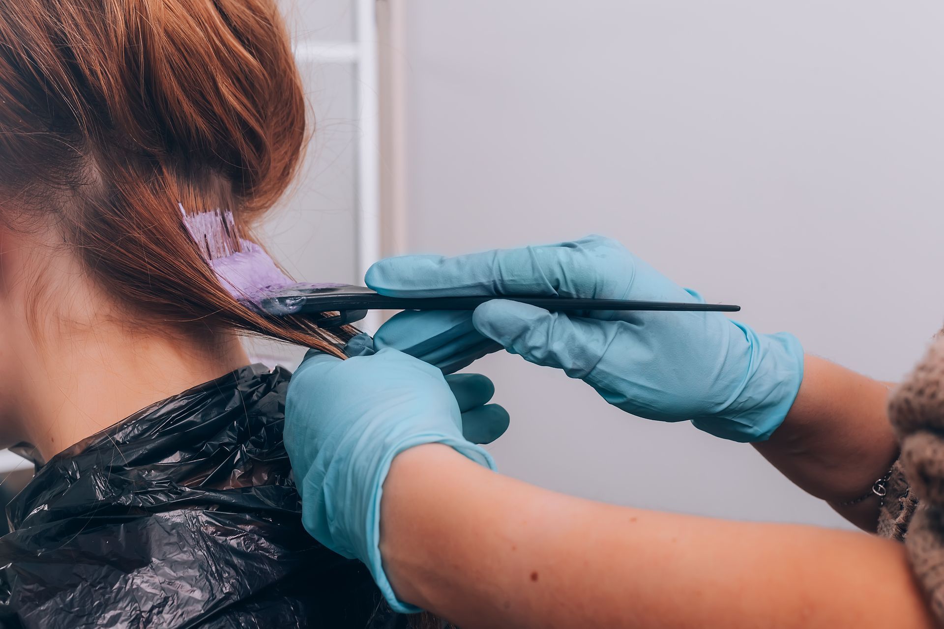 A woman is getting her hair dyed by a hairdresser.