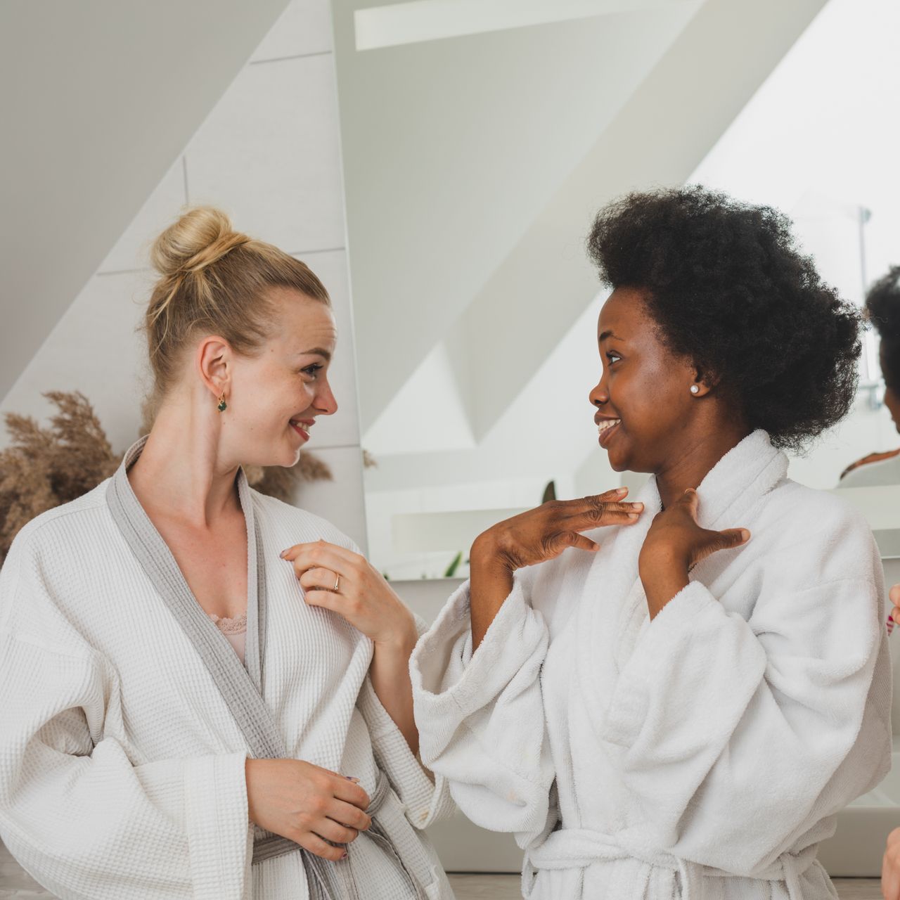 Three women in bathrobes are talking to each other in a bathroom