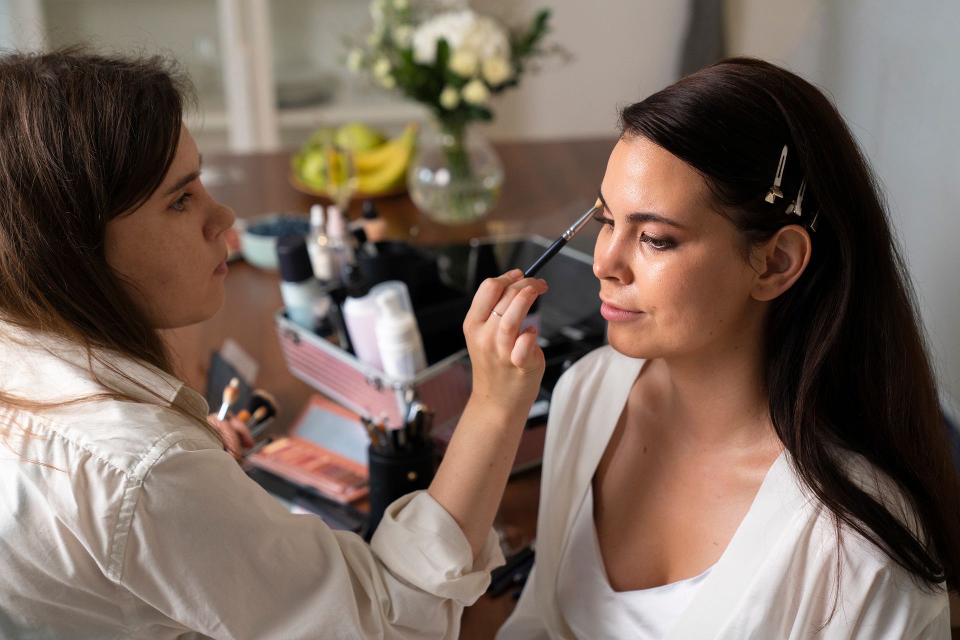 A woman is getting her makeup done by a makeup artist.