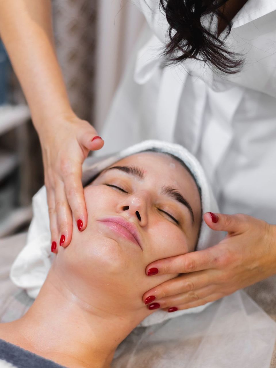 A woman is getting a facial massage in a spa.