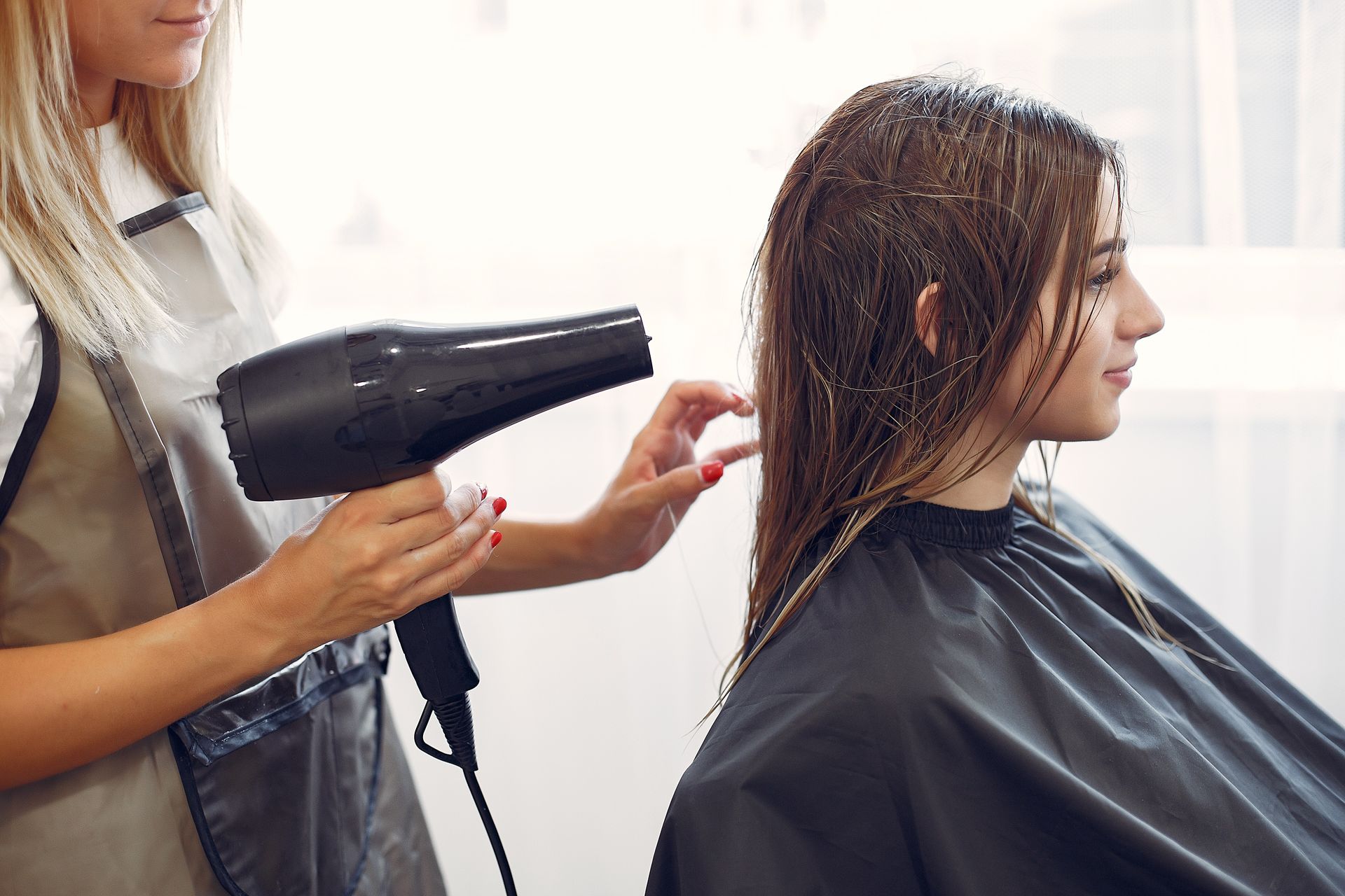 A woman is getting her hair blow dried by a hairdresser in a salon.