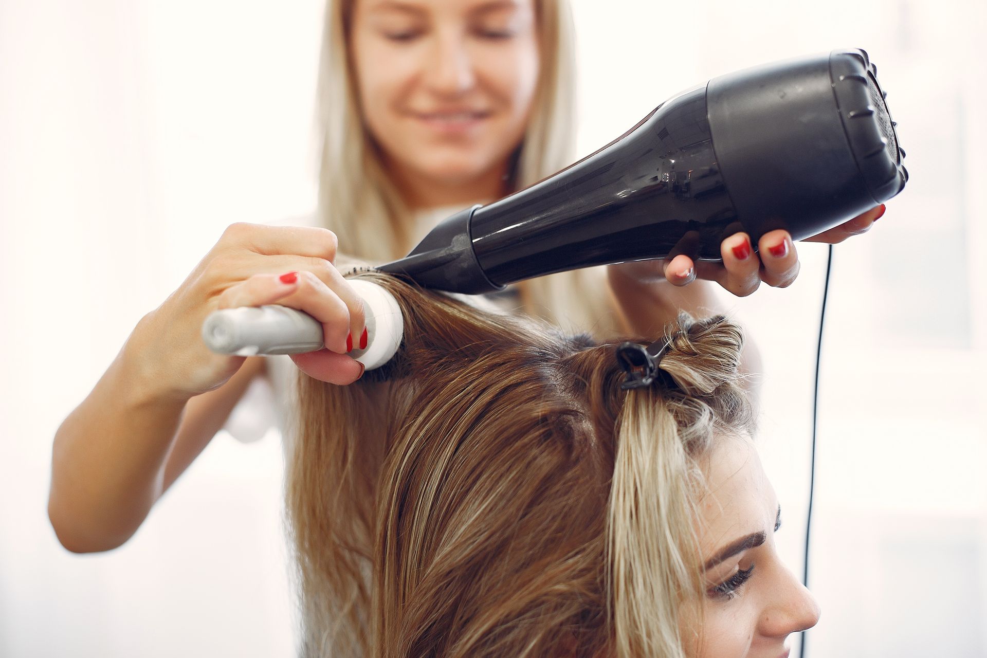 A woman is getting her hair blow dried by a hairdresser.