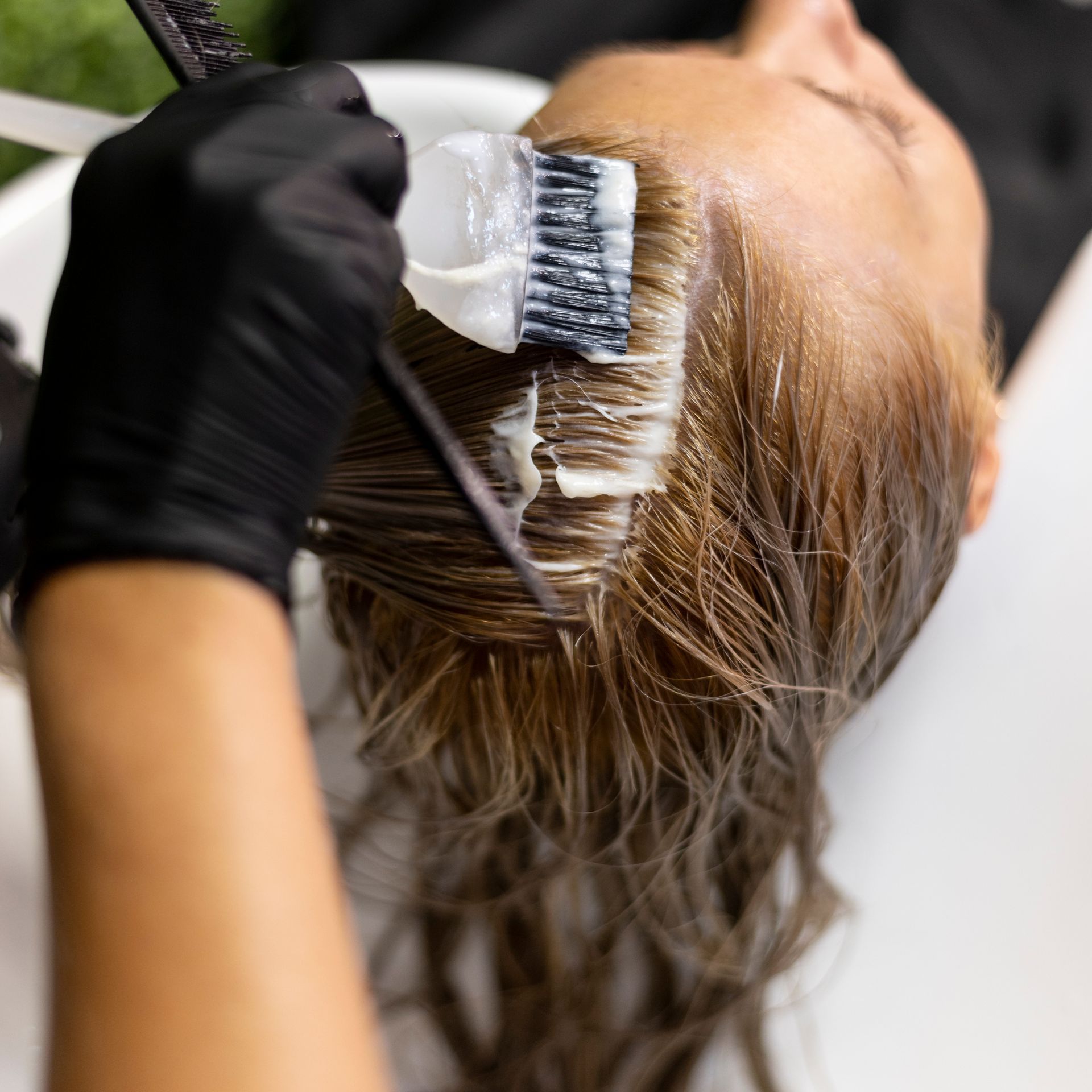 A woman is getting her hair dyed in a salon.