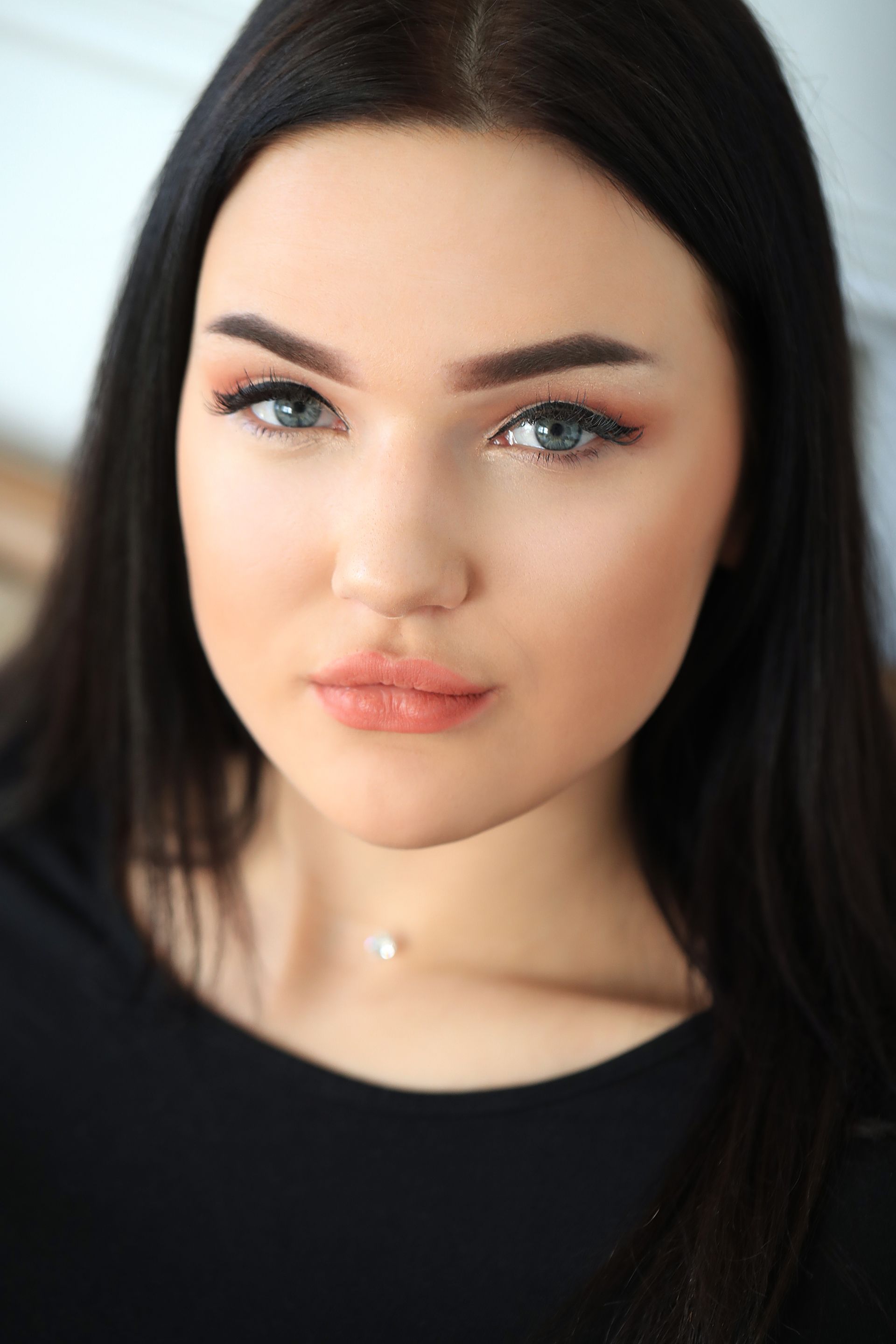 A close up of a woman 's face with long dark hair and blue eyes.