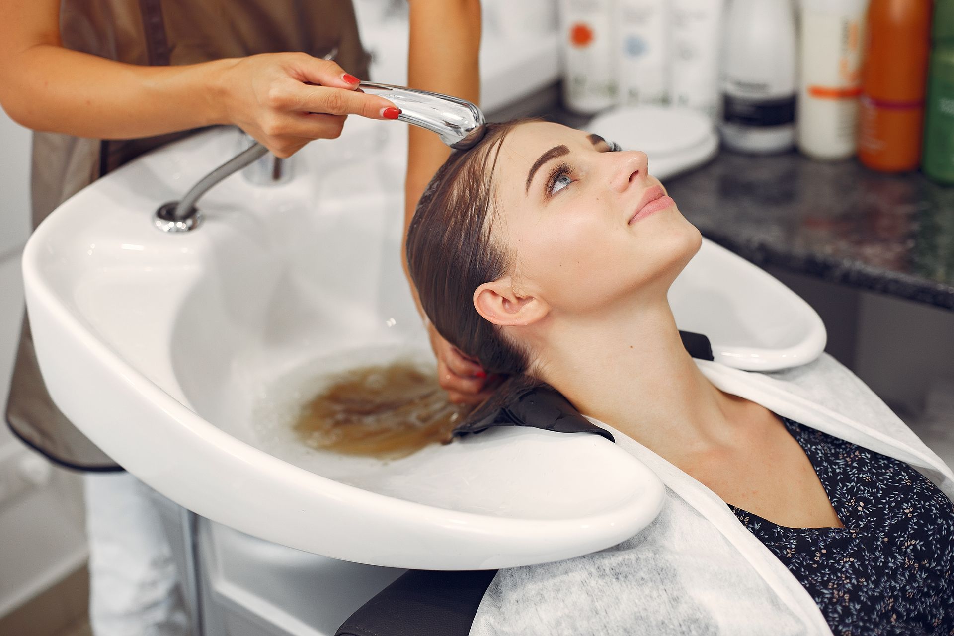 A woman is getting her hair washed in a sink at a hair salon.