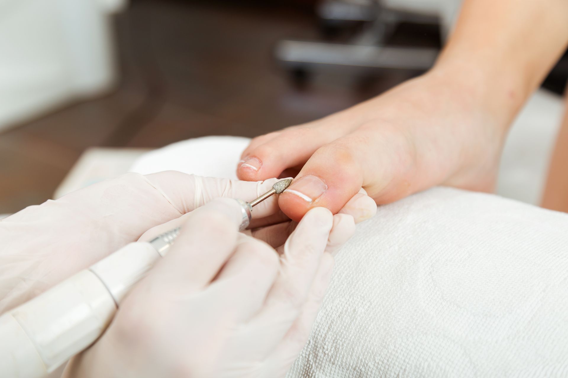 A woman is getting her toenails painted by a nail artist.