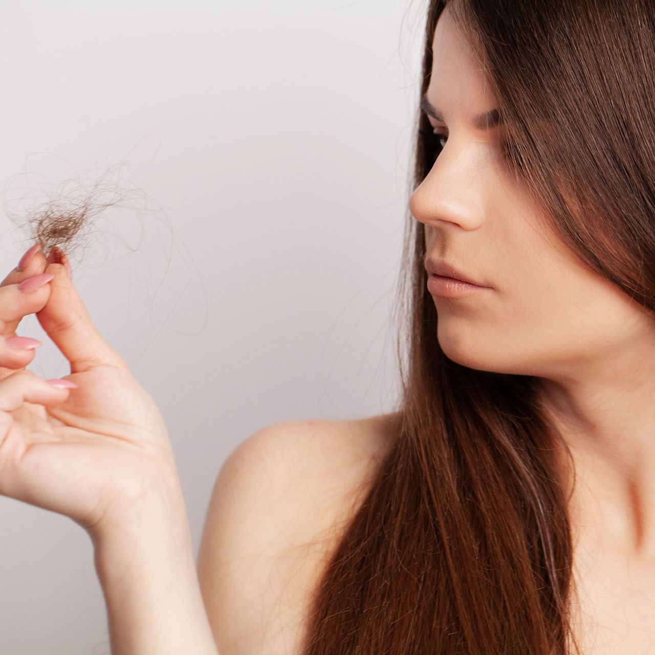 A woman is holding a piece of her hair in her hand.