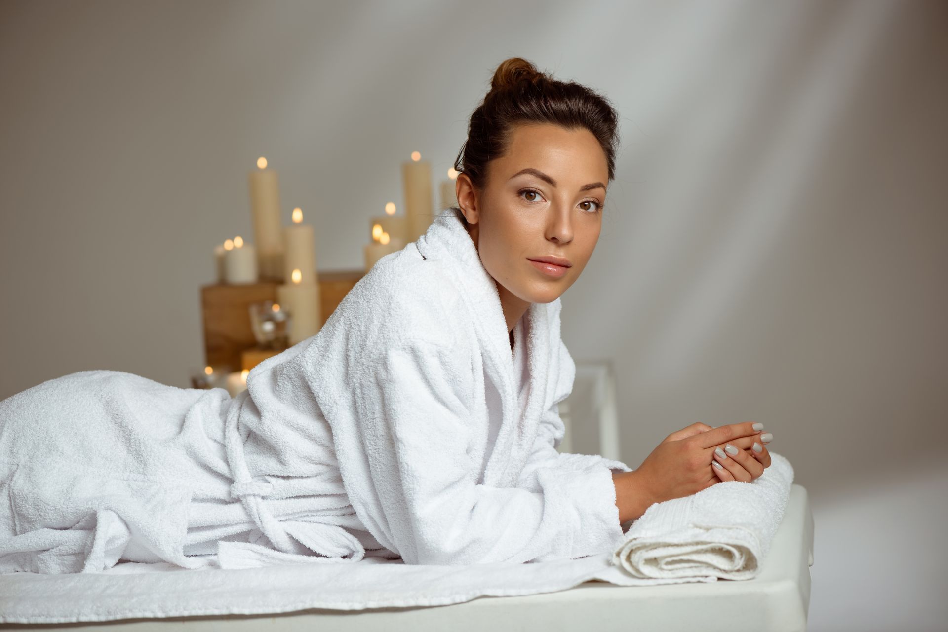 A woman in a bathrobe is laying on a table in a spa.