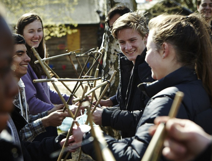 A group of people are playing with sticks and smiling